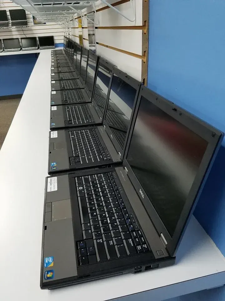 A row of laptops are lined up on a table