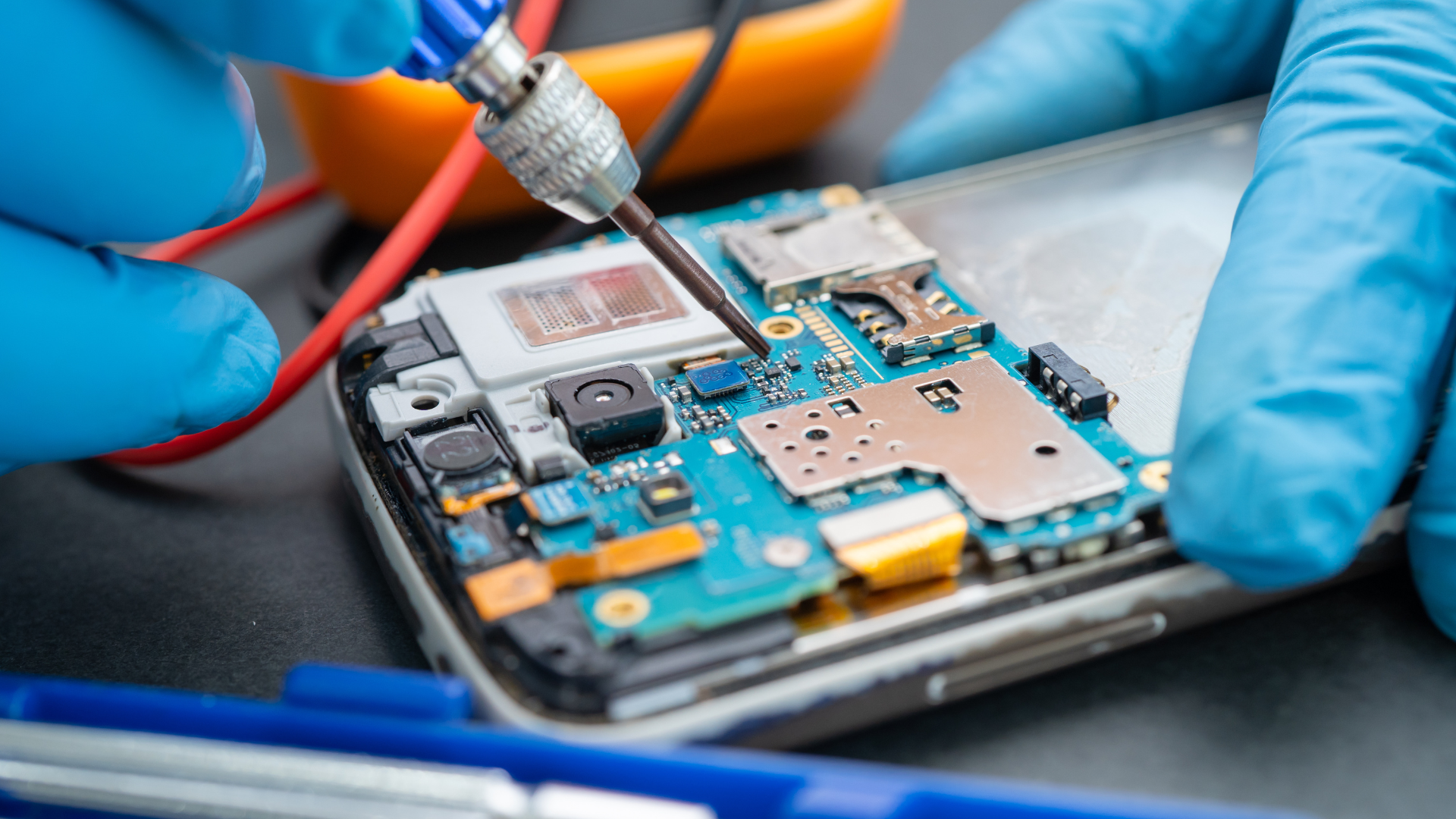 A person is repairing a cell phone with a soldering iron.