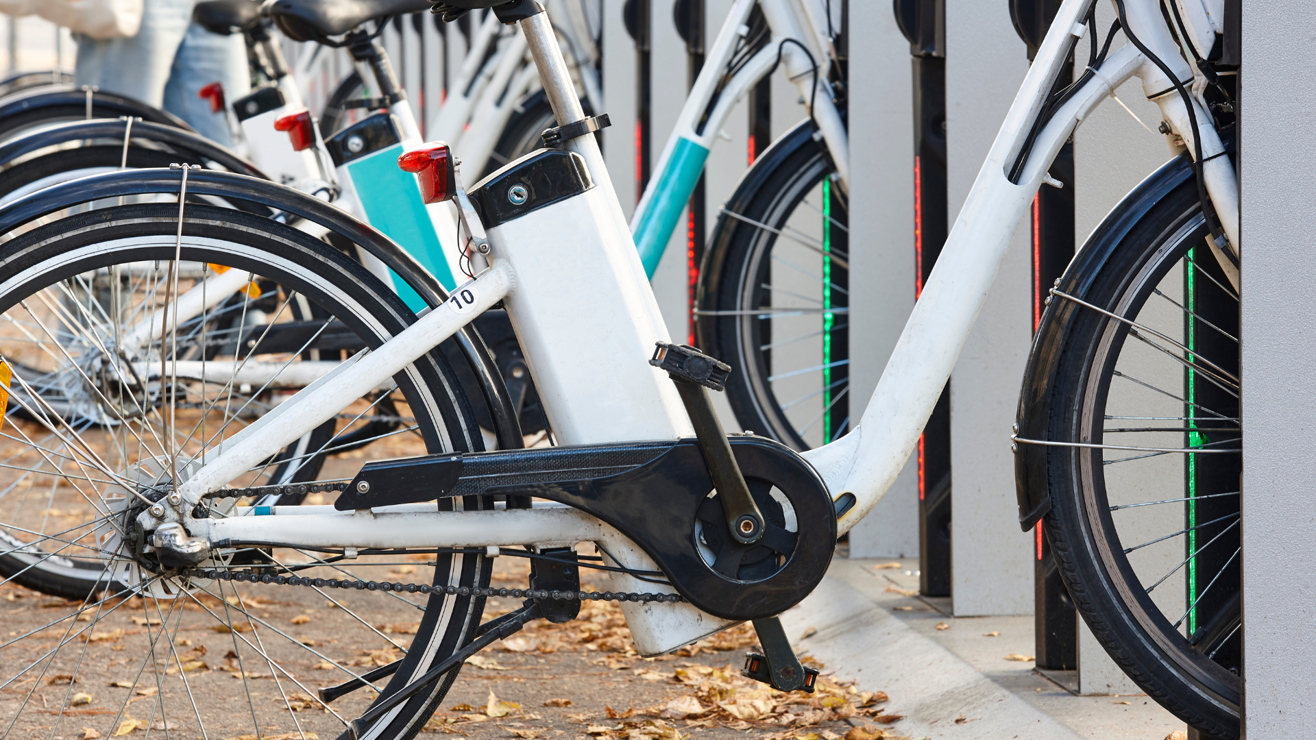 A row of bicycles are parked next to each other in a parking lot.