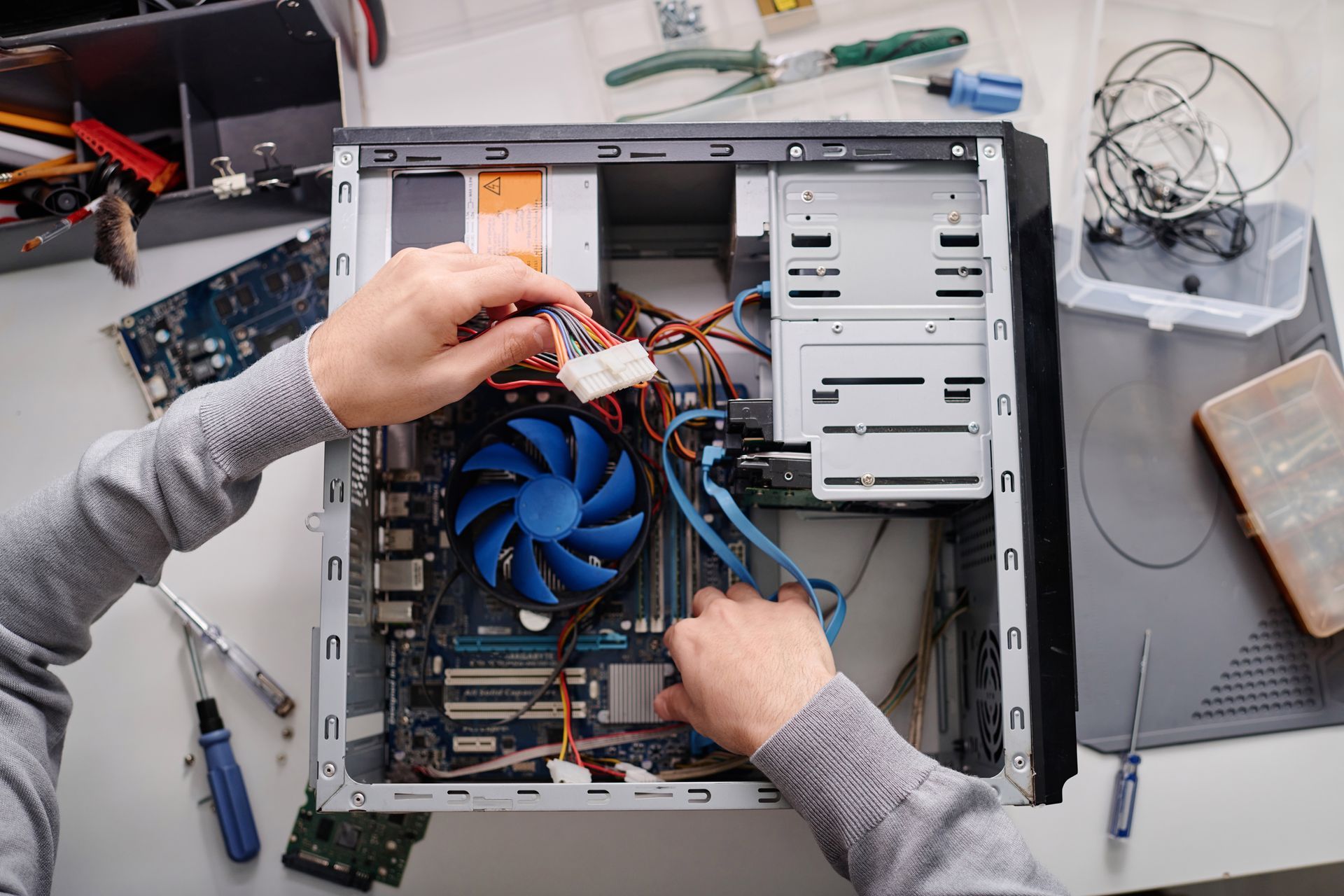 A person is fixing a computer with a fan.