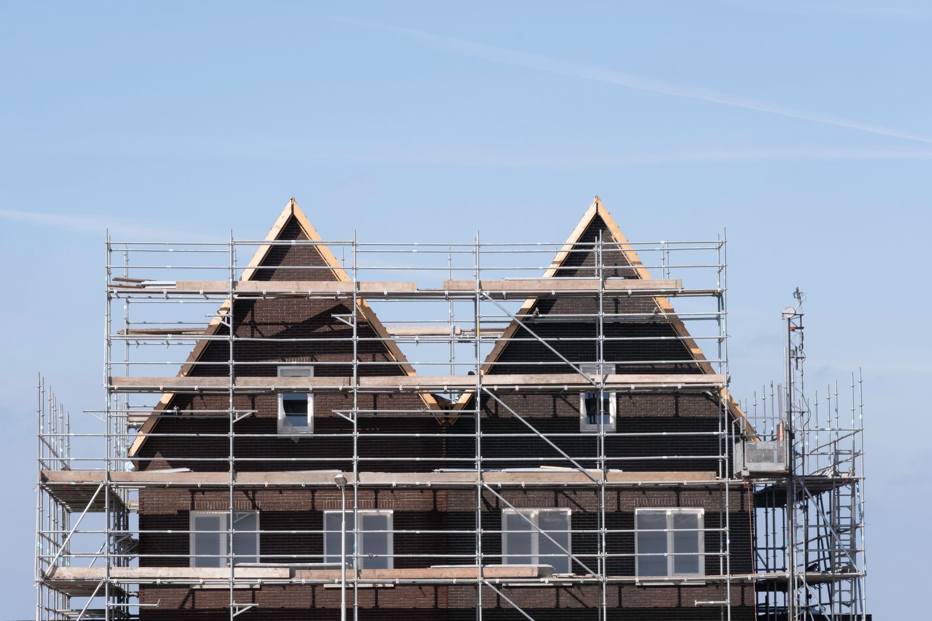 Scaffolding pile platform against two identical newly built terraced houses on a construction site.