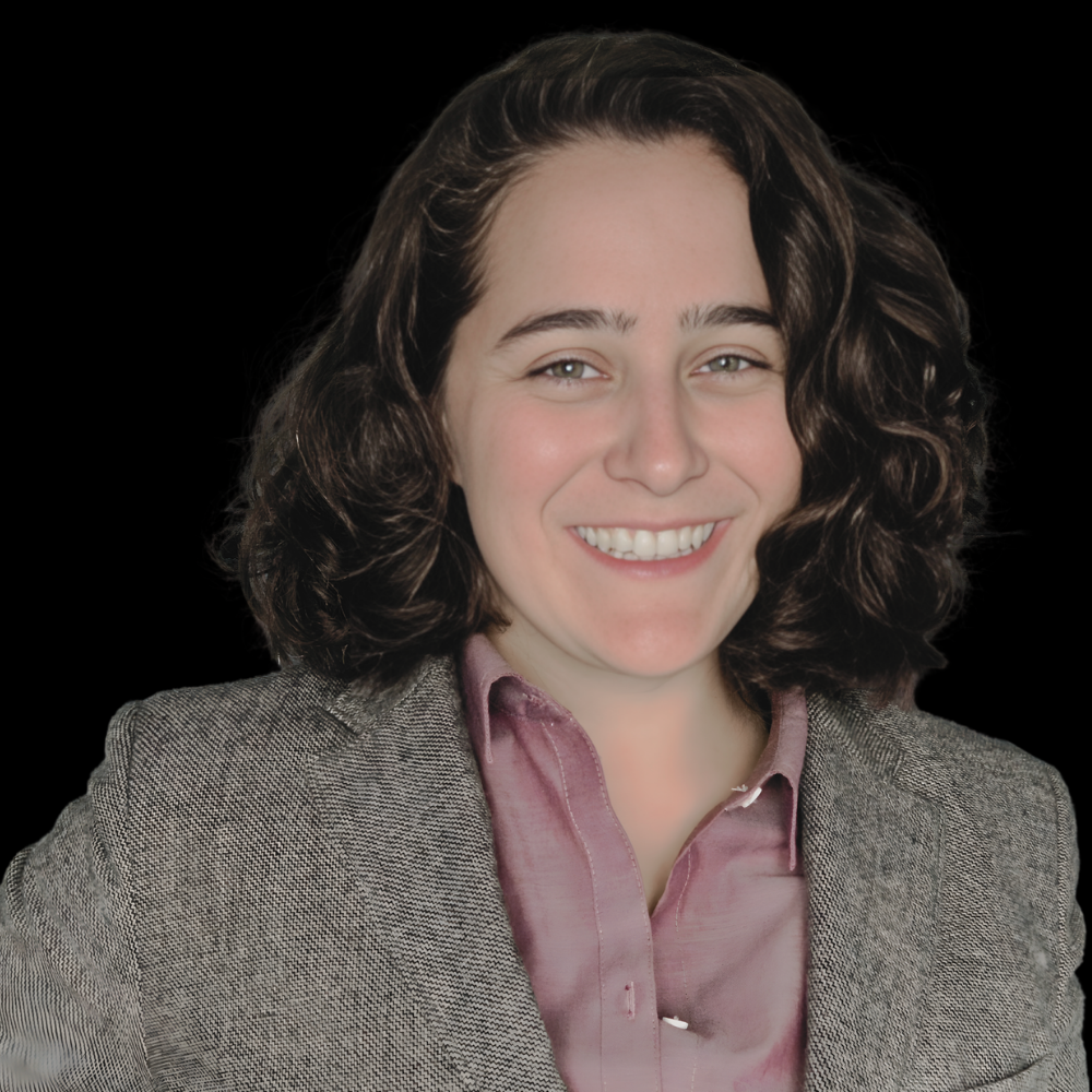 White woman with brown shoulder-length hair in a blazer smiling against a grey background