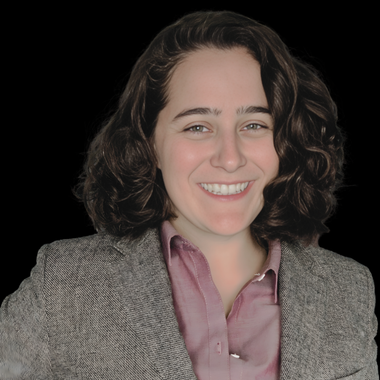 White woman with brown shoulder-length hair in a blazer smiling against a grey background