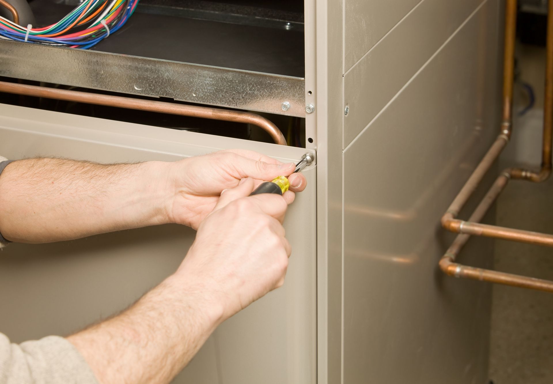 Technician performing furnace repair in Newberg, OR, using a screwdriver to ensure efficient heating