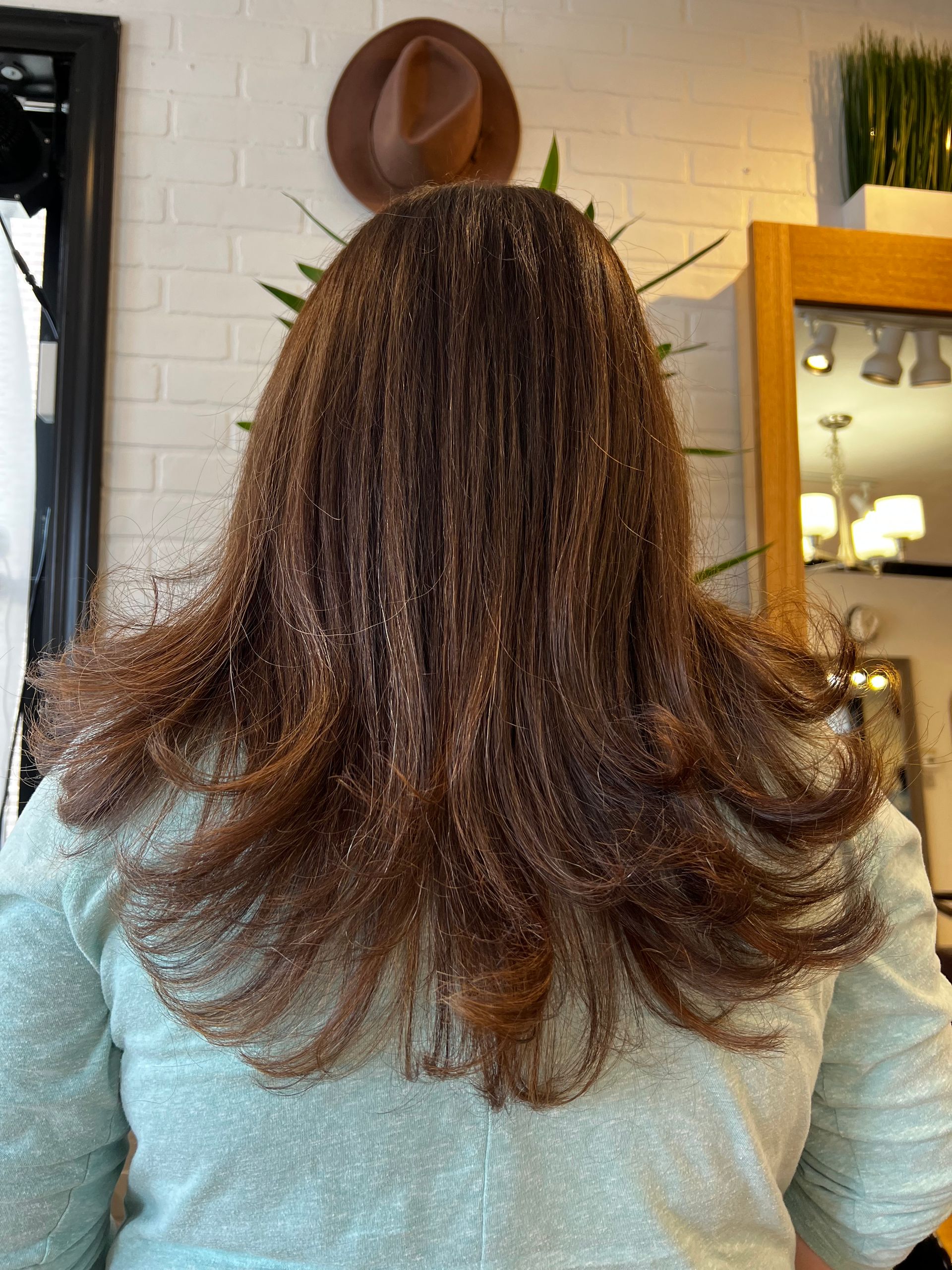 A woman with long brown hair is standing in front of a mirror