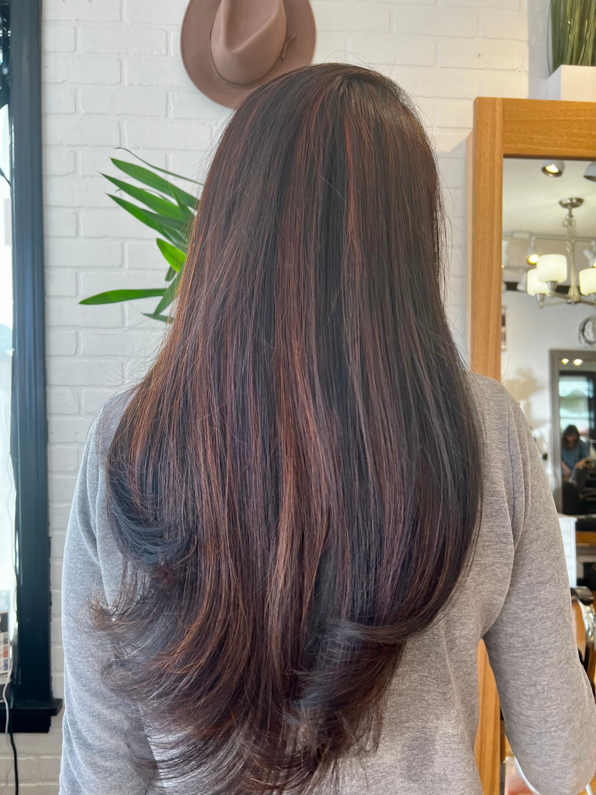 A woman with long brown hair is standing in front of a mirror.