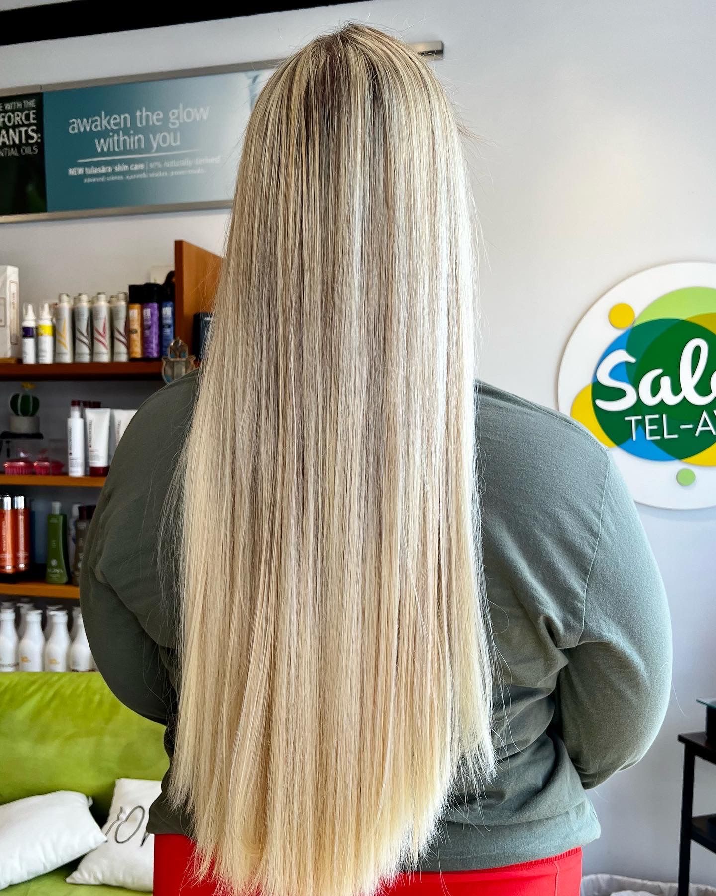 A woman with long blonde hair is standing in a salon