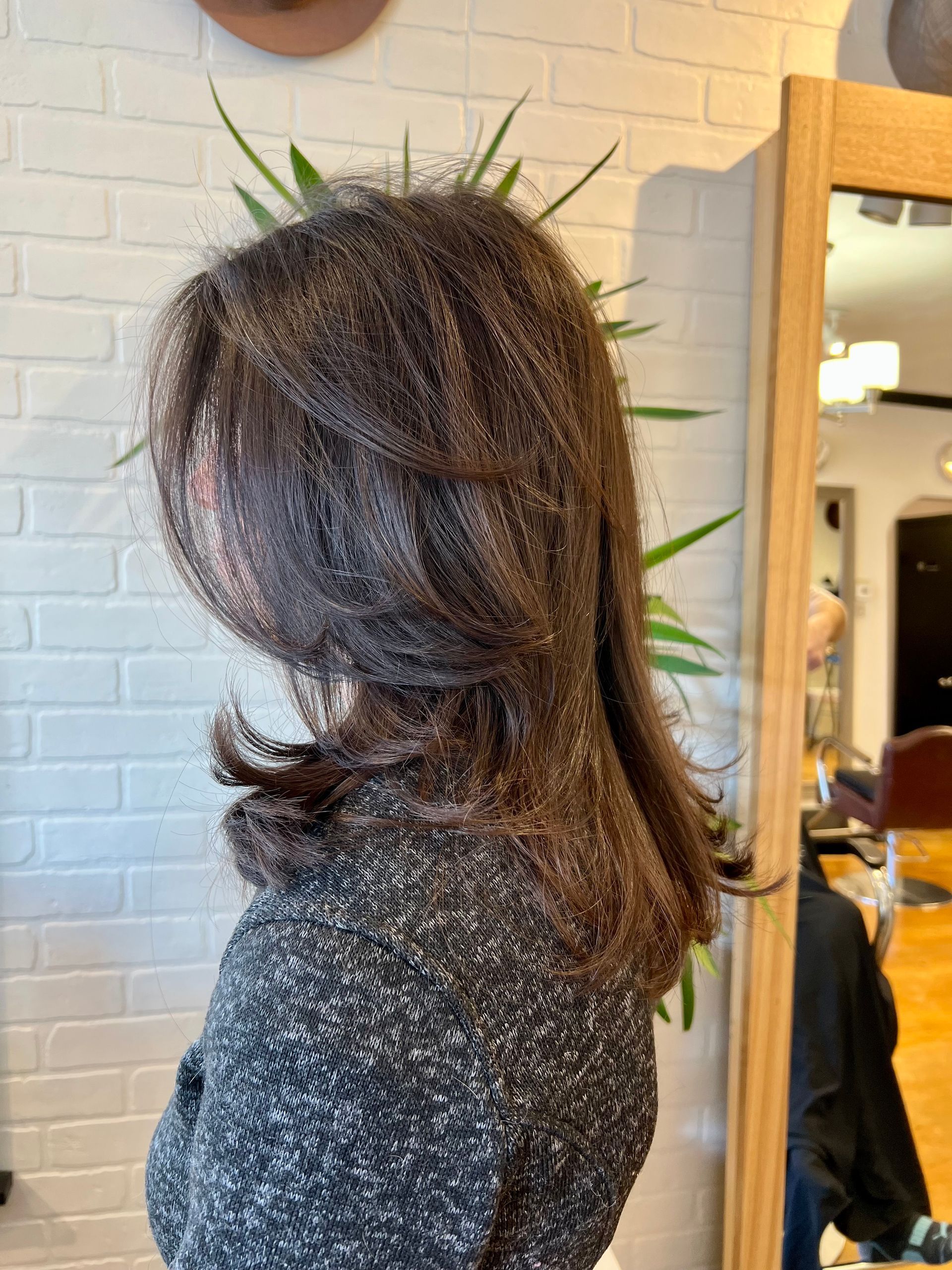 A woman with long hair is standing in front of a mirror.