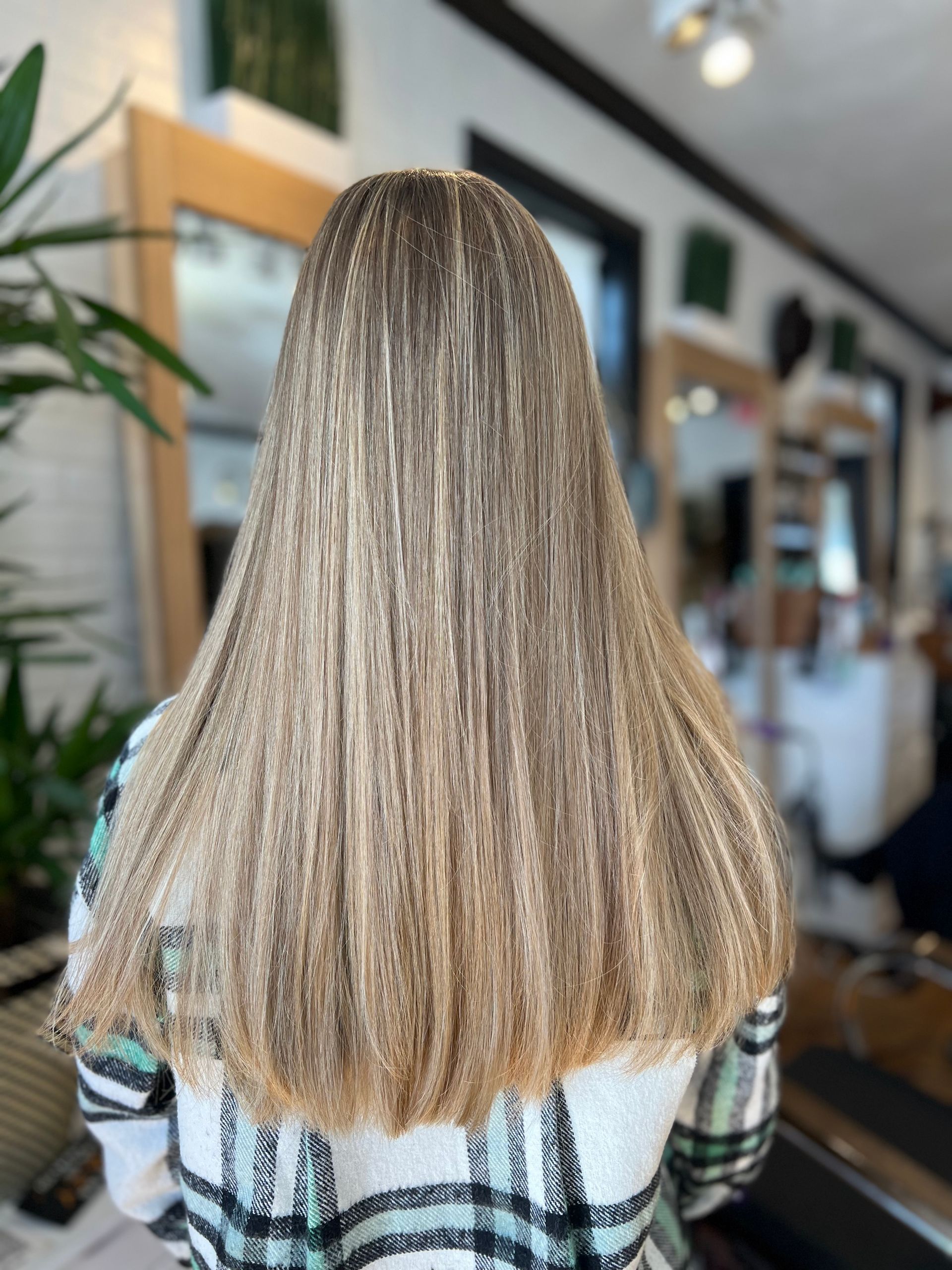 A woman with long blonde hair is wearing a plaid shirt