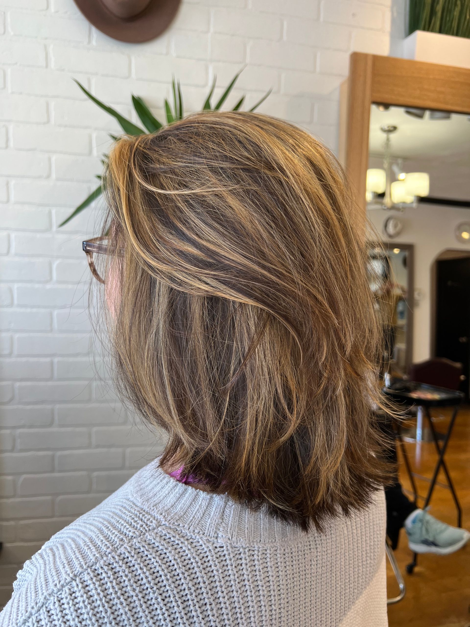 A woman is sitting in front of a mirror with her hair in a ponytail.