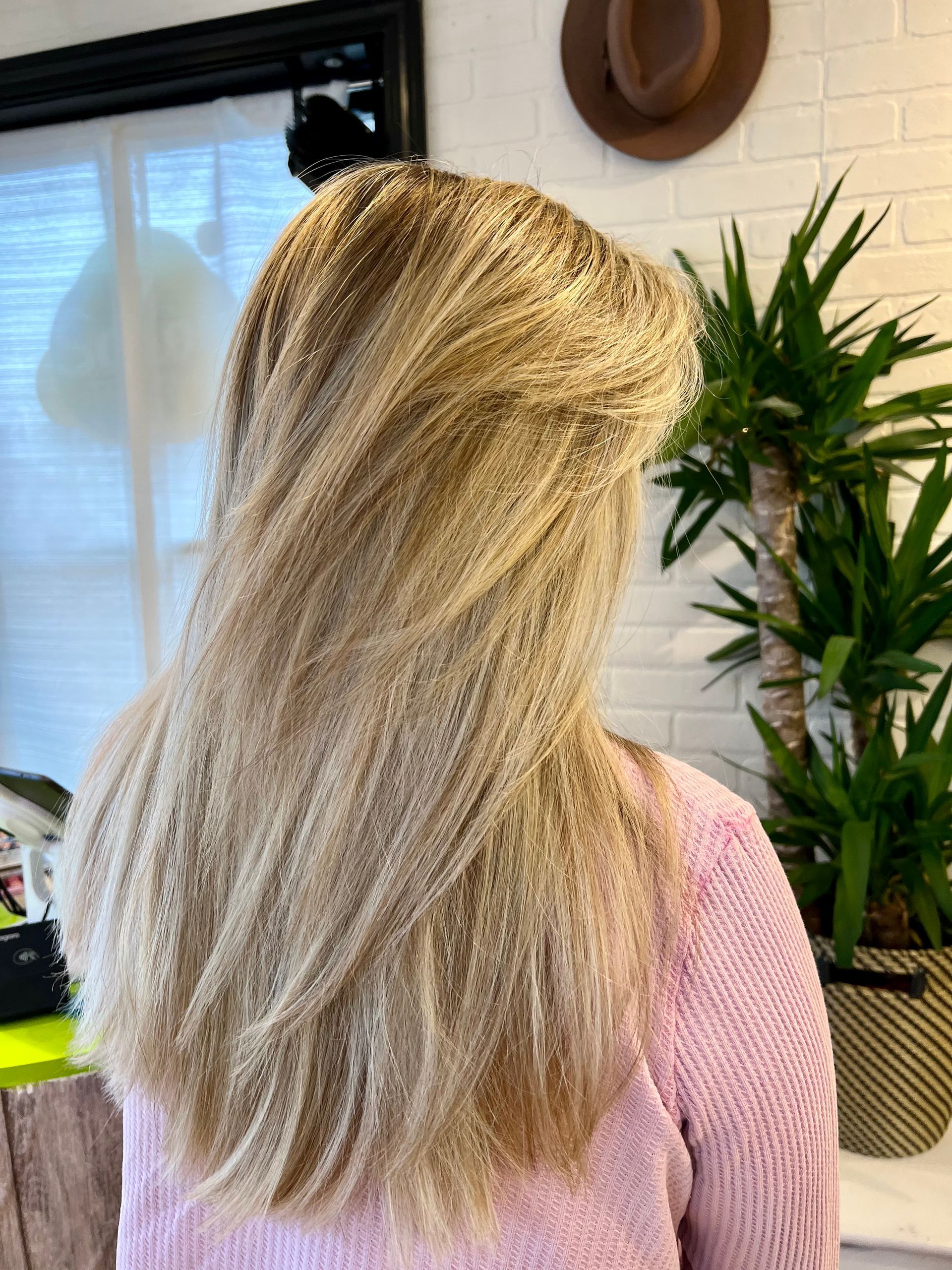 A woman with long blonde hair is wearing a pink sweater.