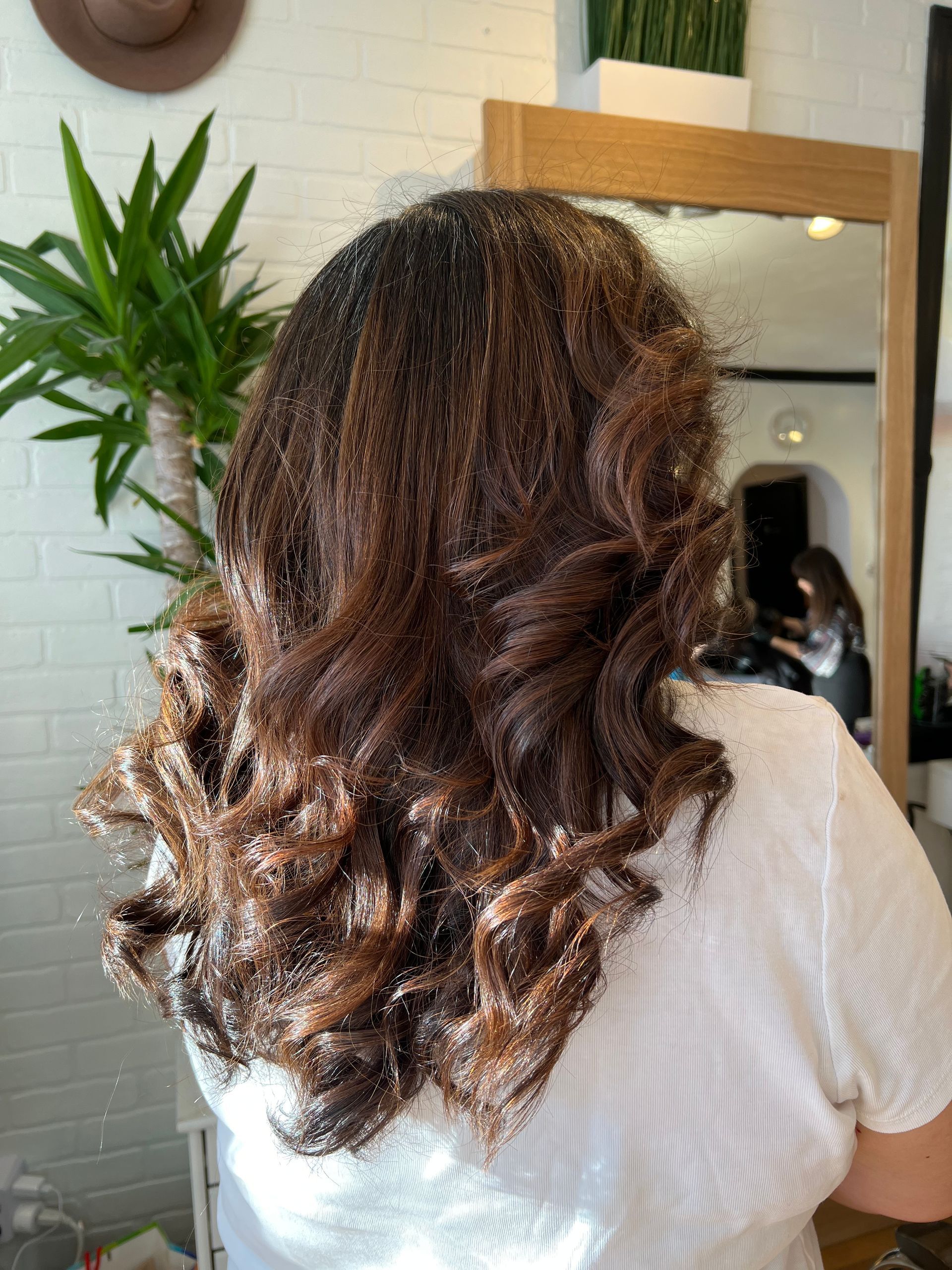 A woman with curly hair is standing in front of a mirror.