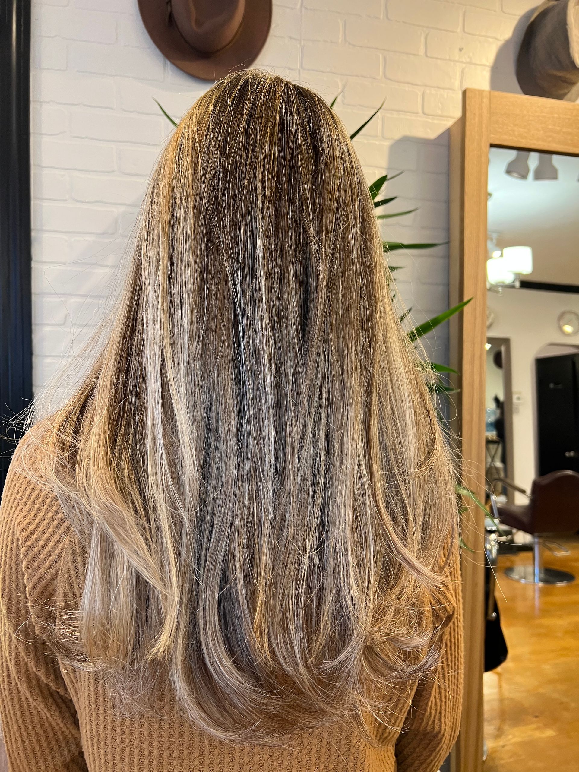 A woman with long blonde hair is standing in front of a mirror.