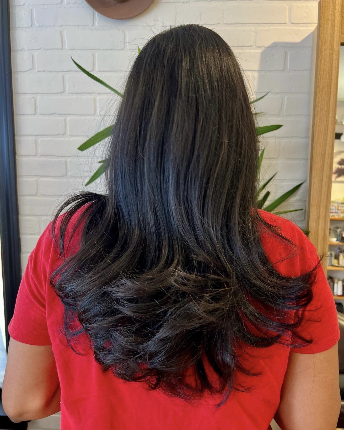 A woman with long black hair is wearing a red shirt.