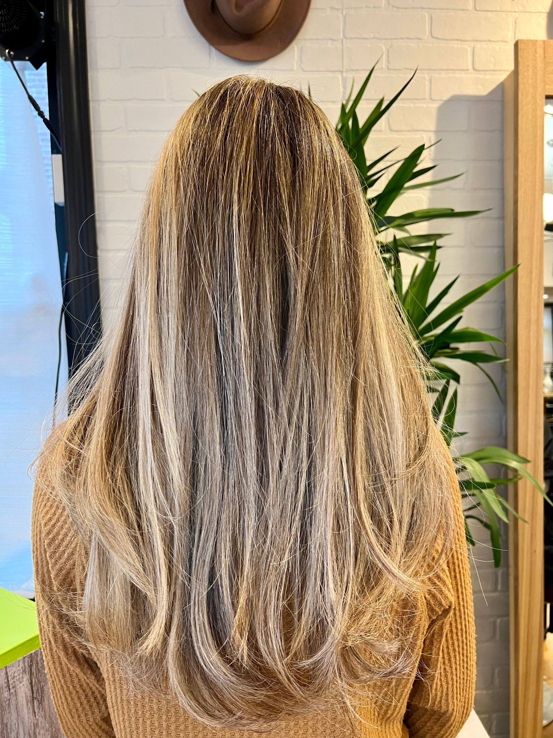 A woman with long blonde hair is standing in front of a mirror.