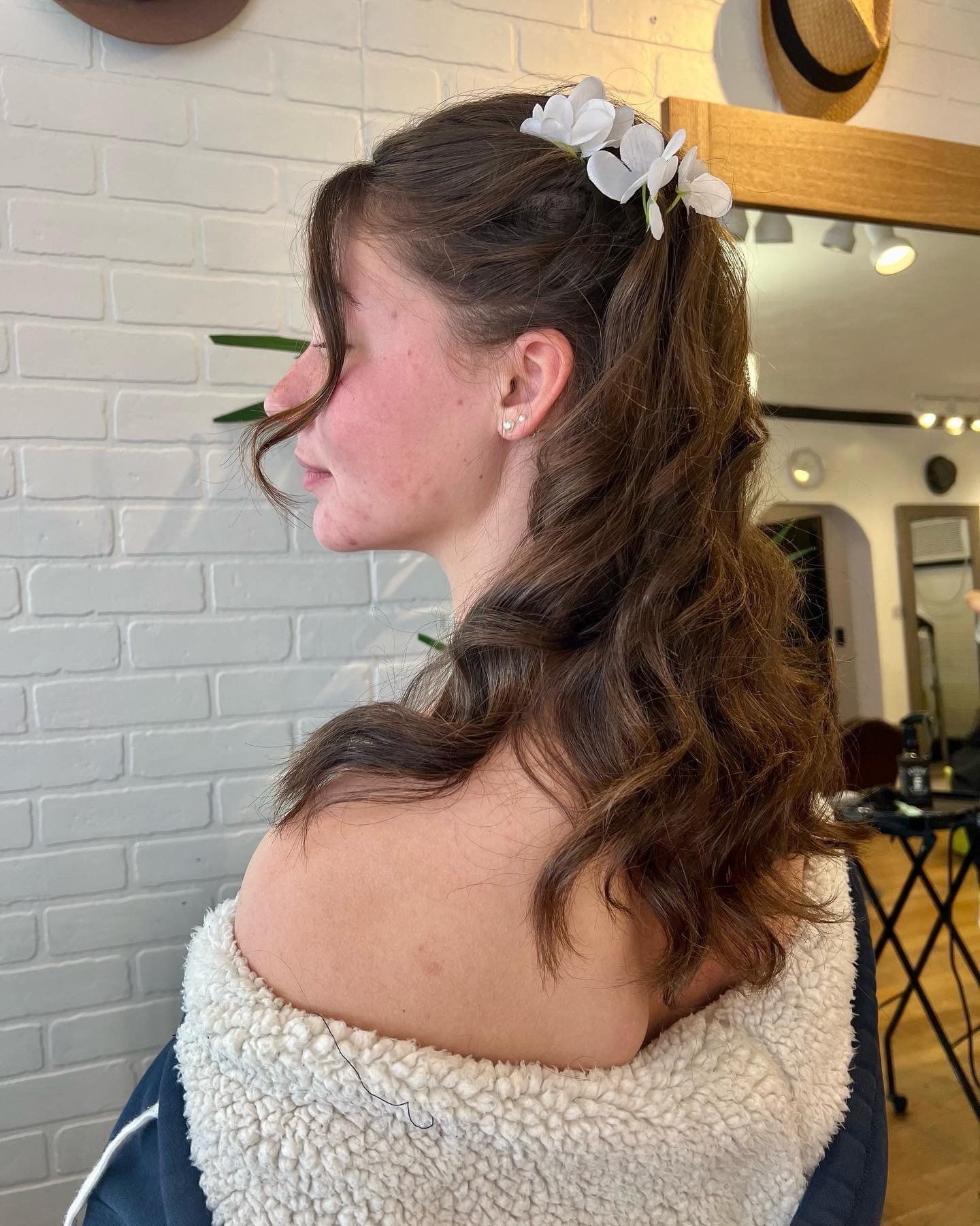 A woman with long hair is wearing a white flower in her hair.