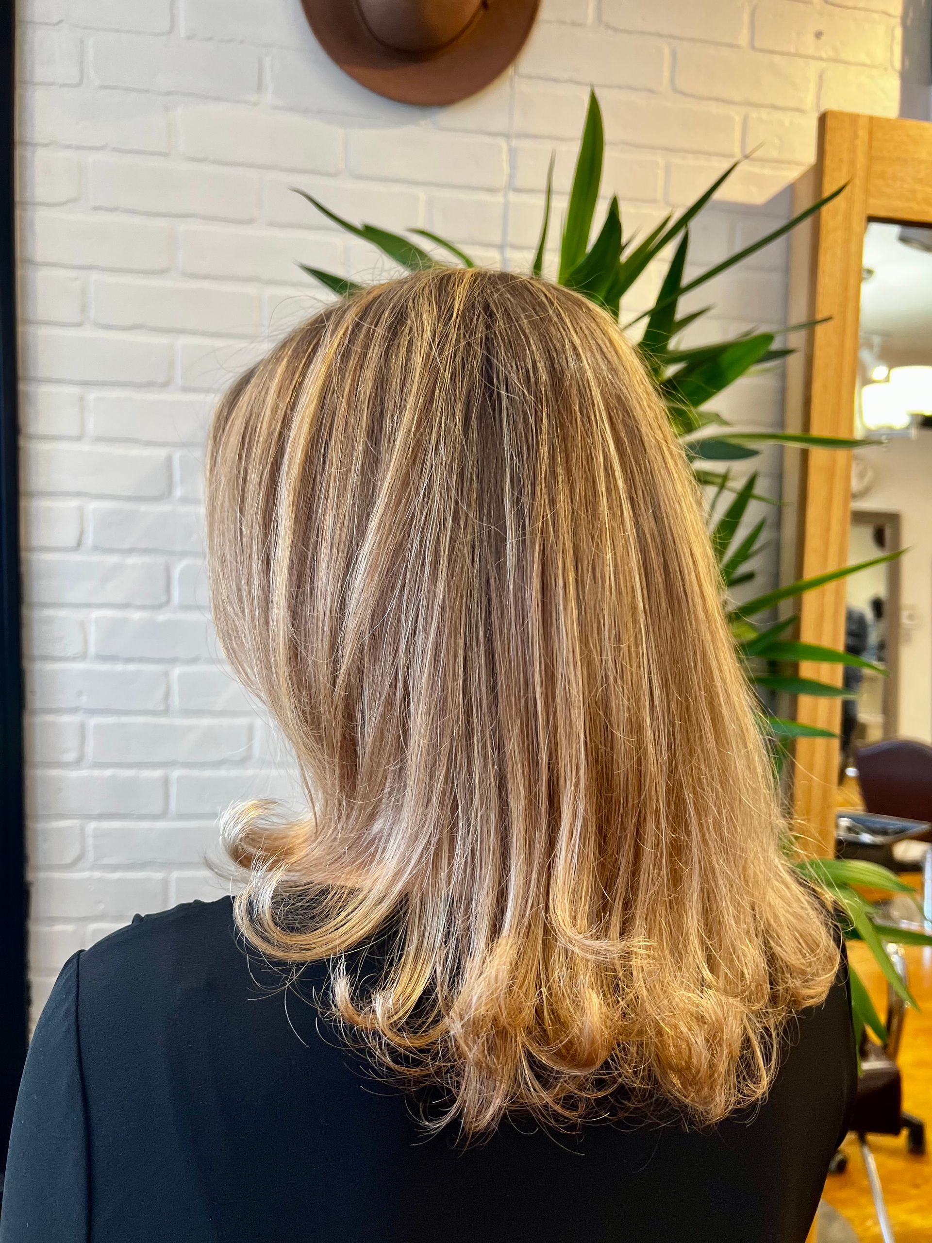 A woman with long blonde hair is sitting in front of a mirror.