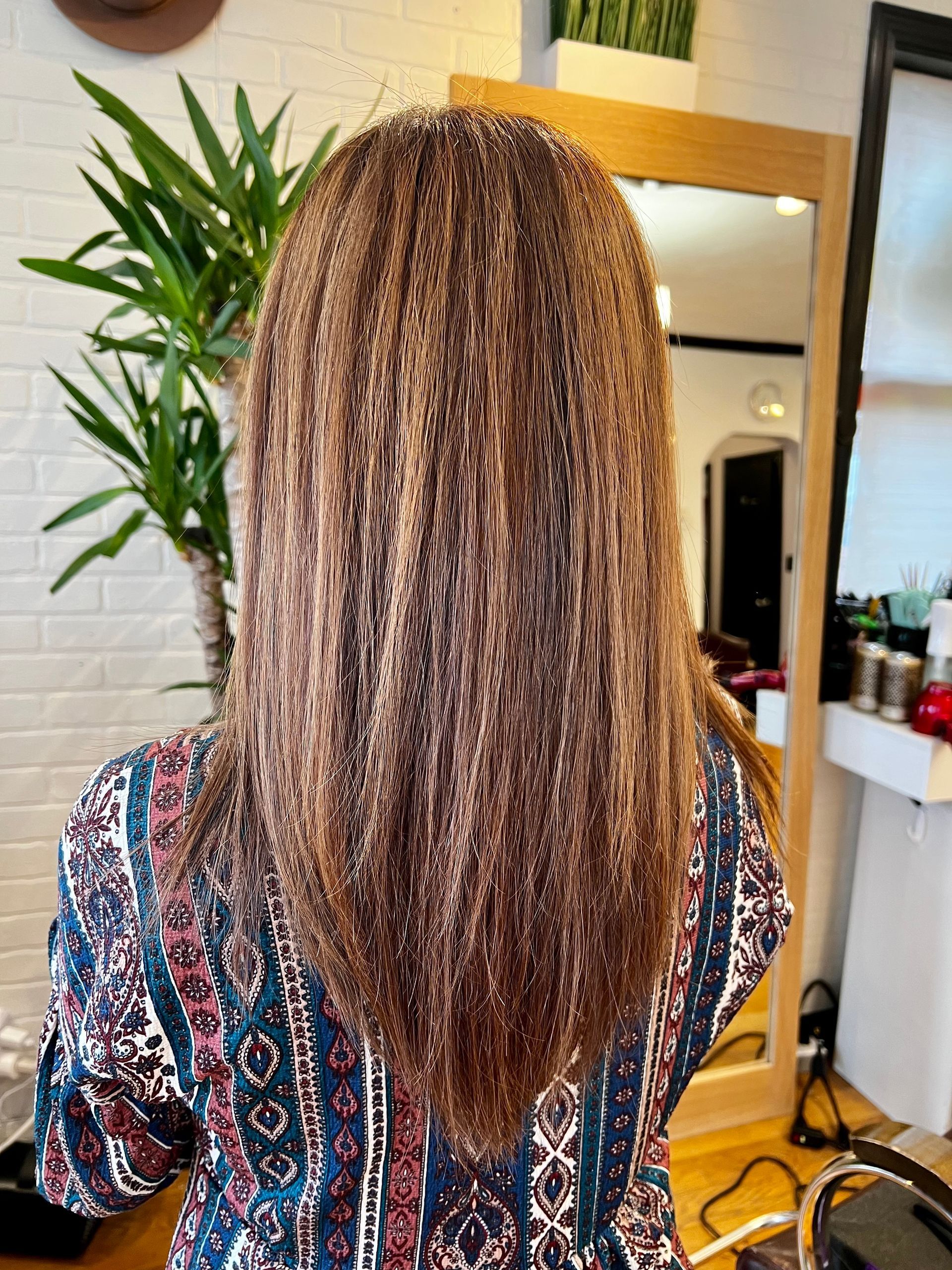 A woman with long hair is standing in front of a mirror.