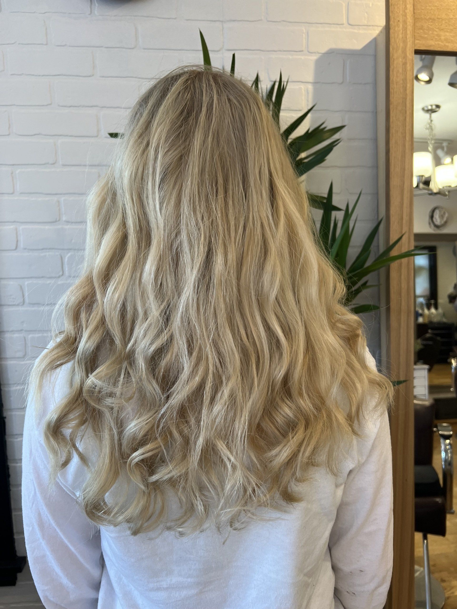 A woman with long blonde hair is standing in front of a mirror.