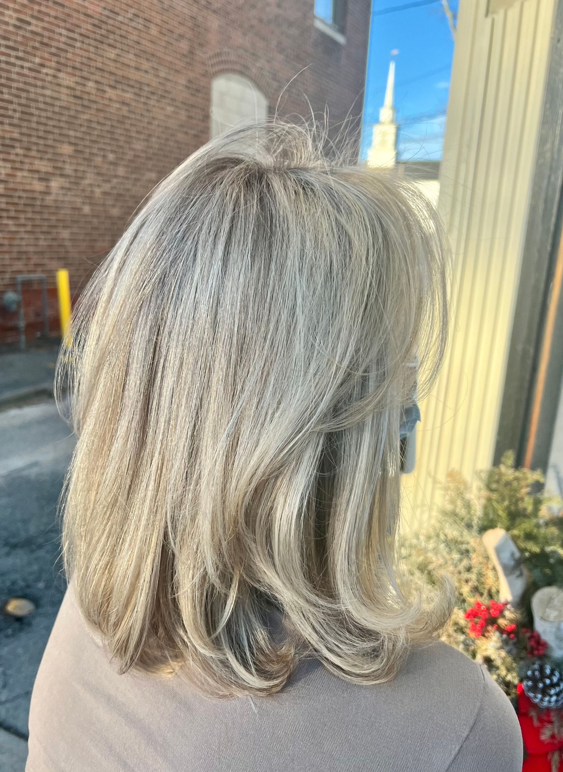 A woman with blonde hair is standing in front of a brick building.