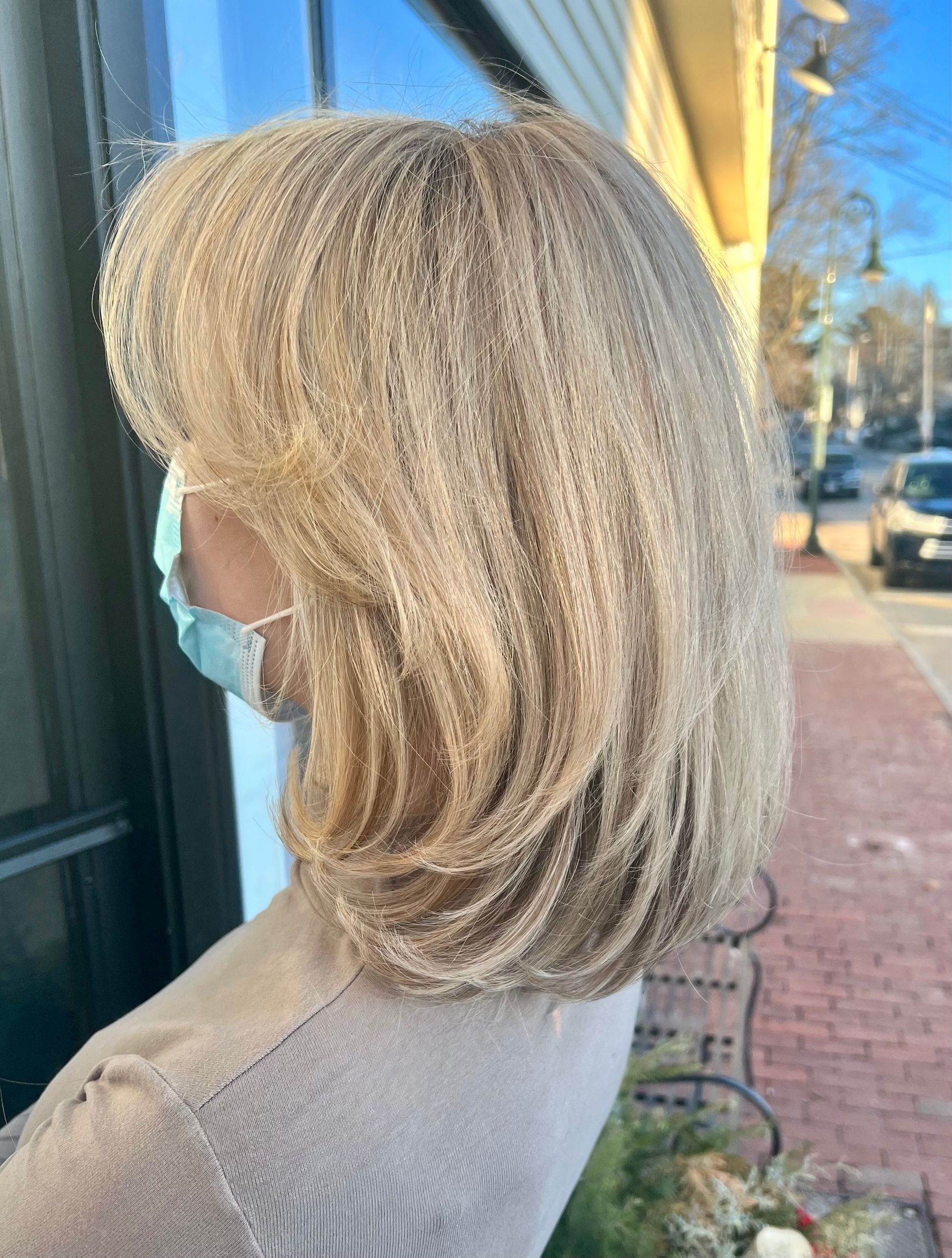 A woman wearing a face mask is standing in front of a window.