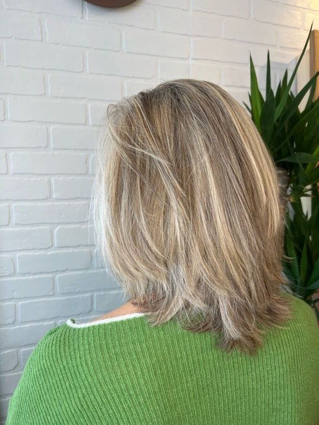 A woman with blonde hair is wearing a green sweater.