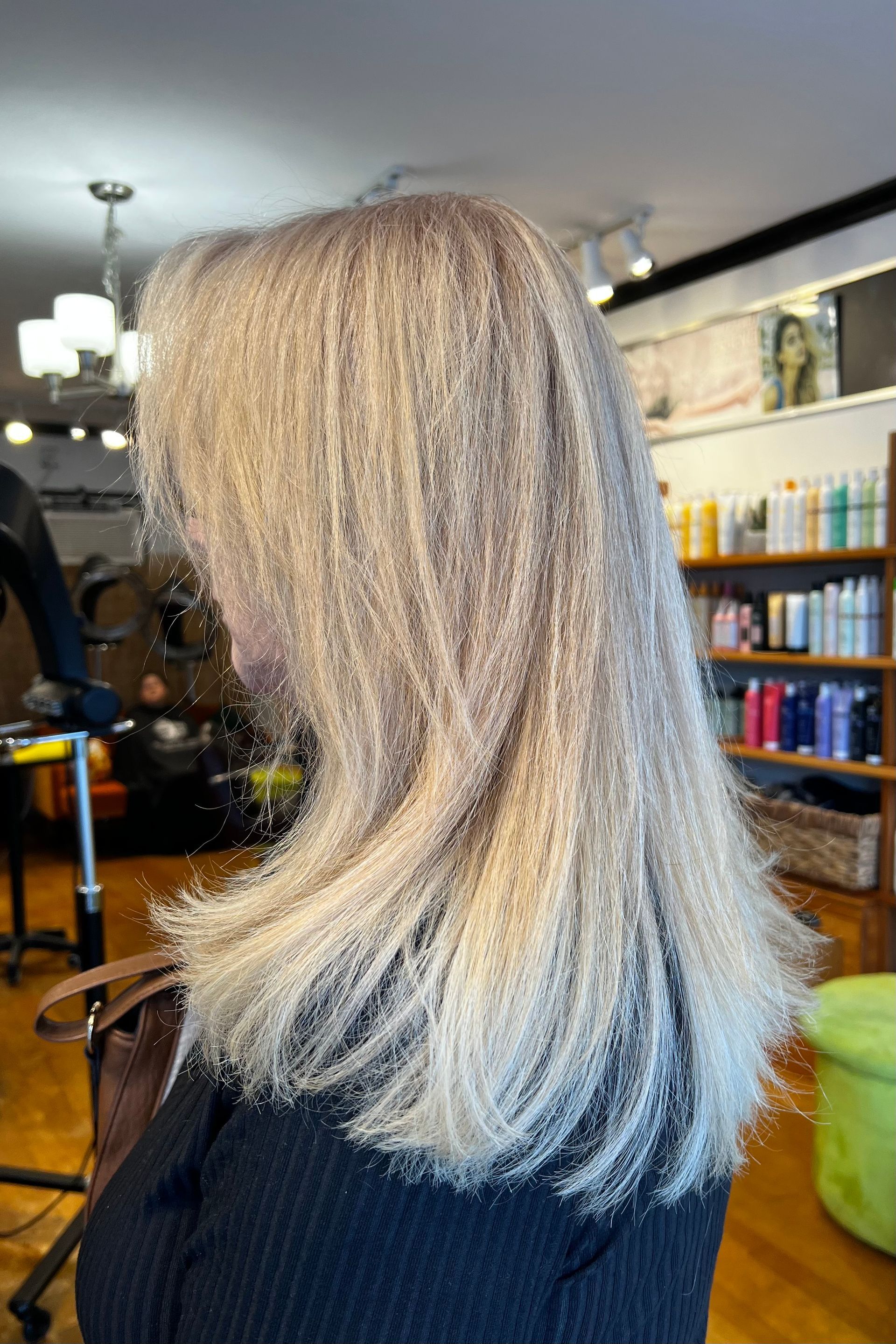 A woman with blonde hair is sitting in a chair in a salon.
