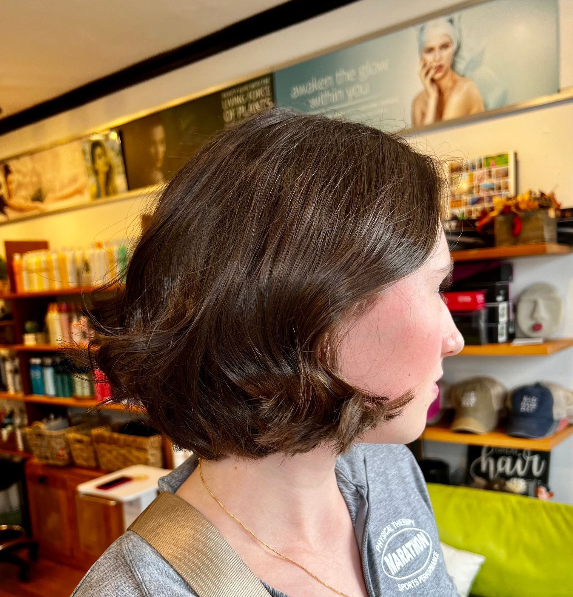 A woman wearing a gray shirt with the word hairdresser on it