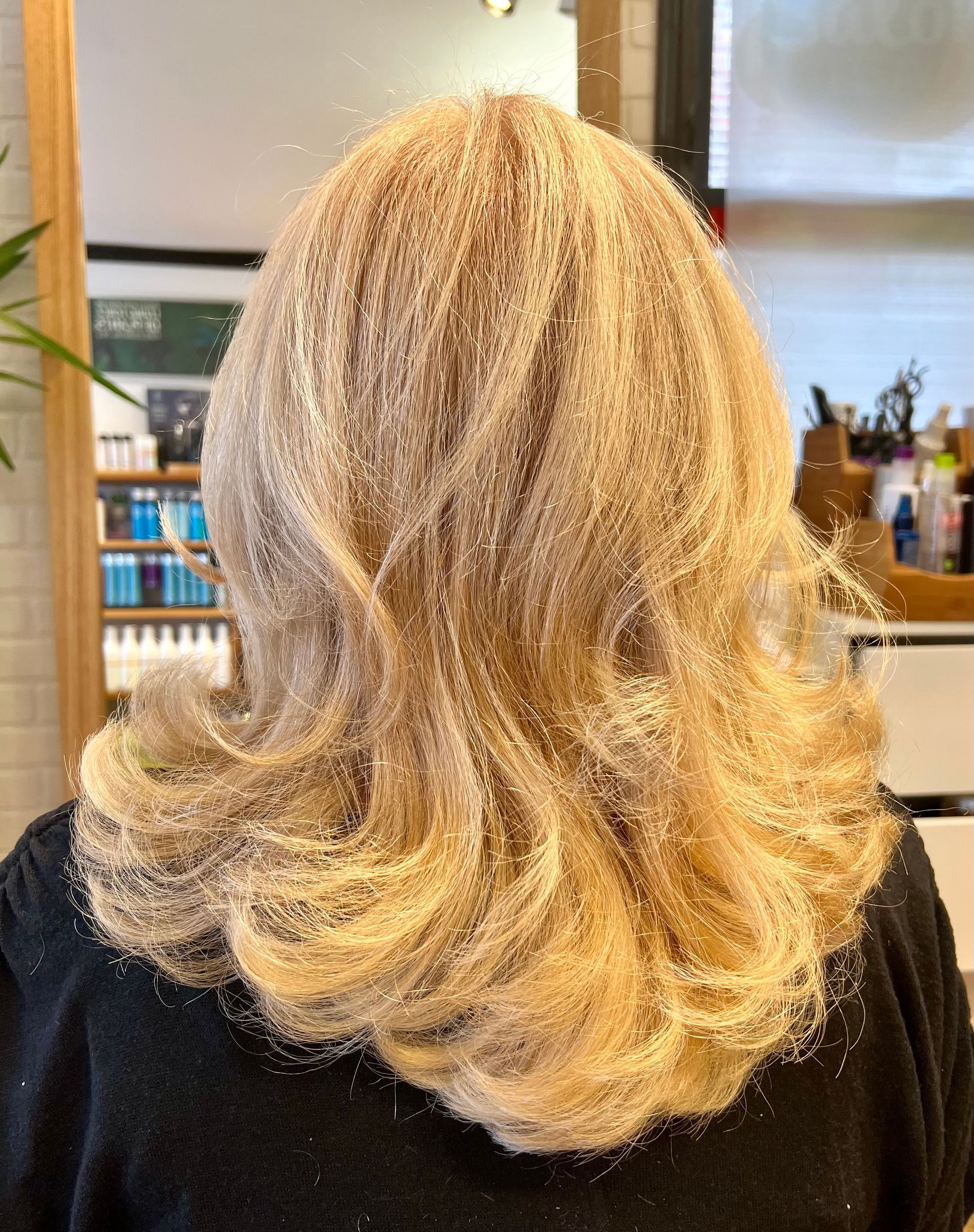 A woman with blonde hair is wearing a black sweater.