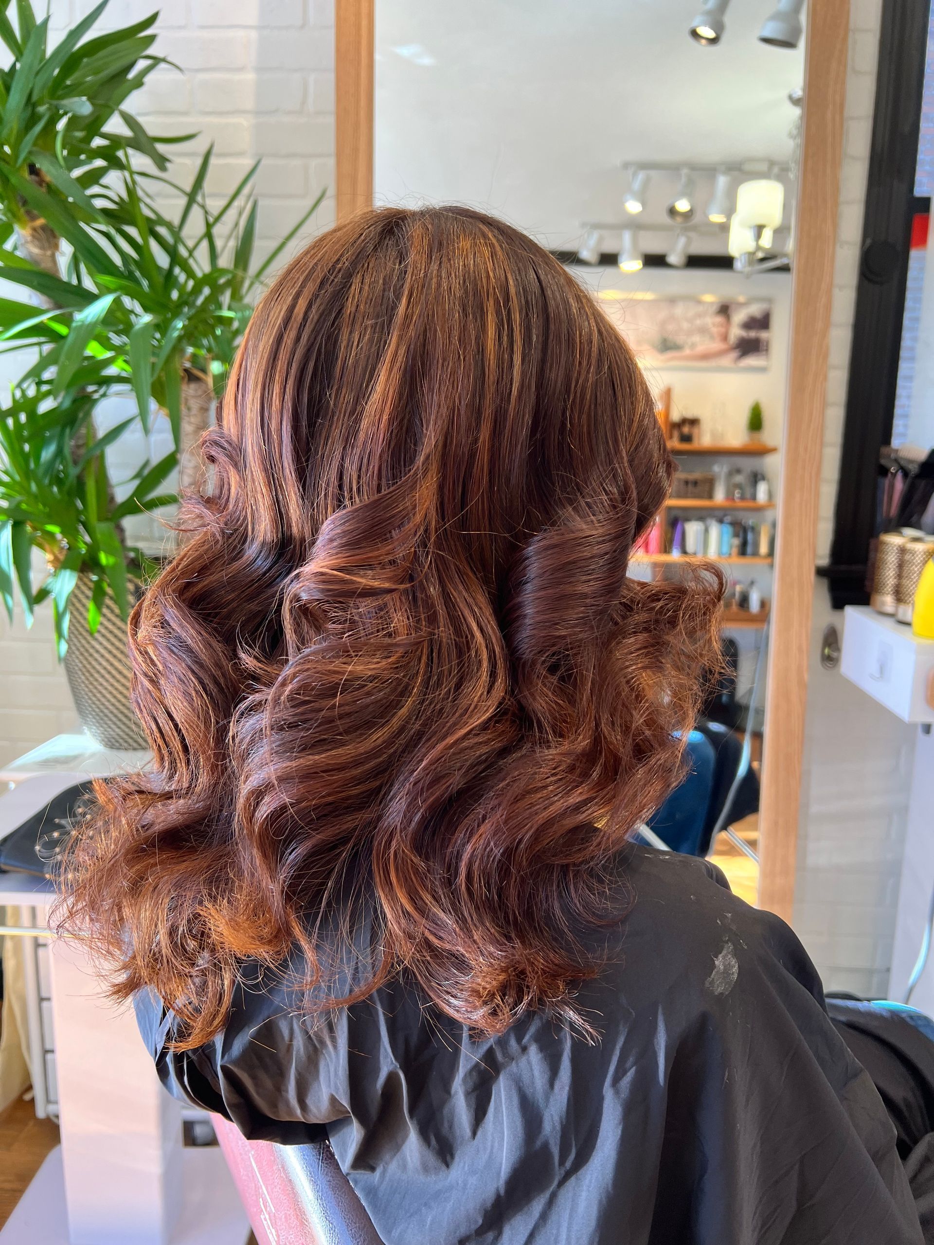 A woman is sitting in a chair with her hair in a salon.