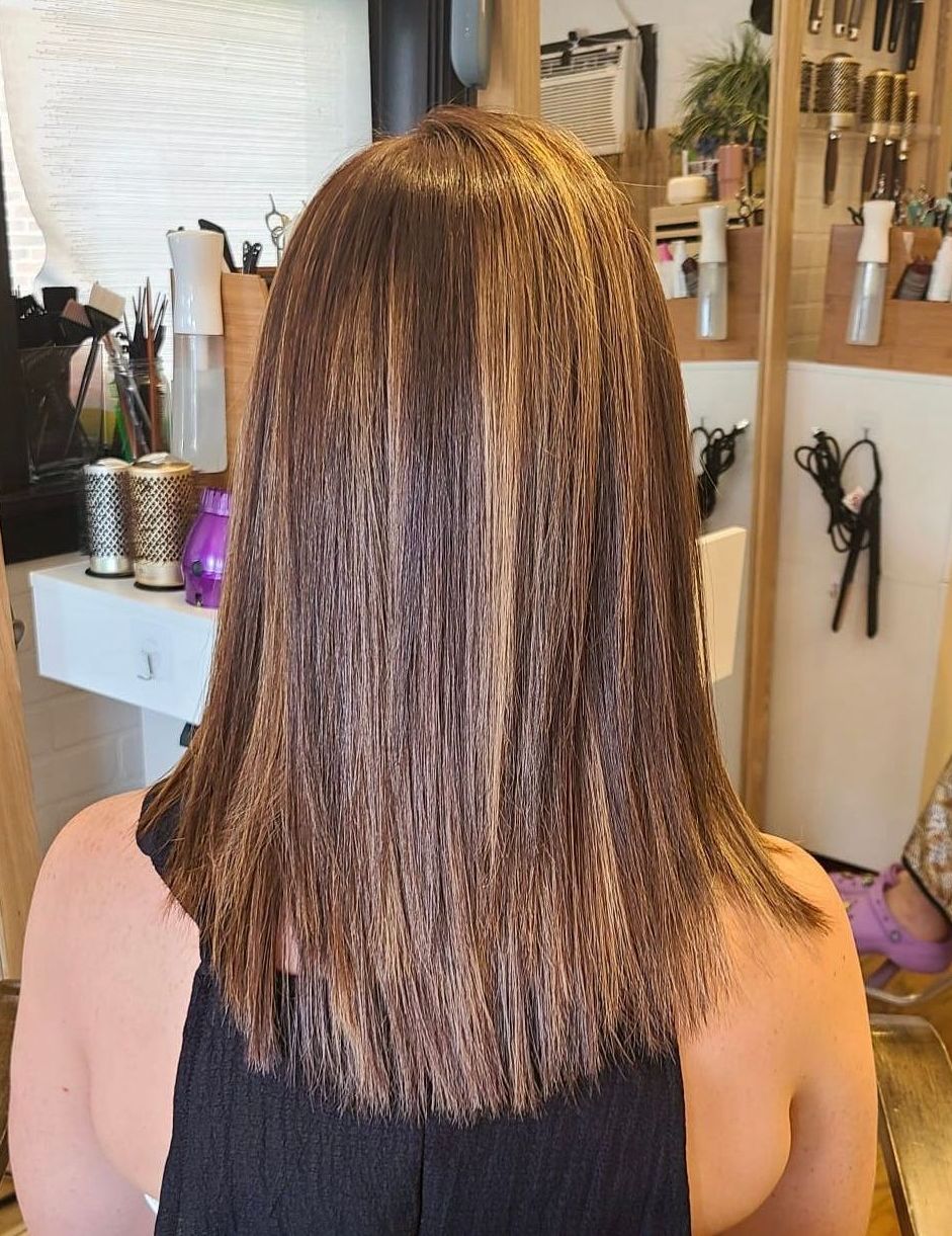 A woman with long brown hair is sitting in front of a mirror.