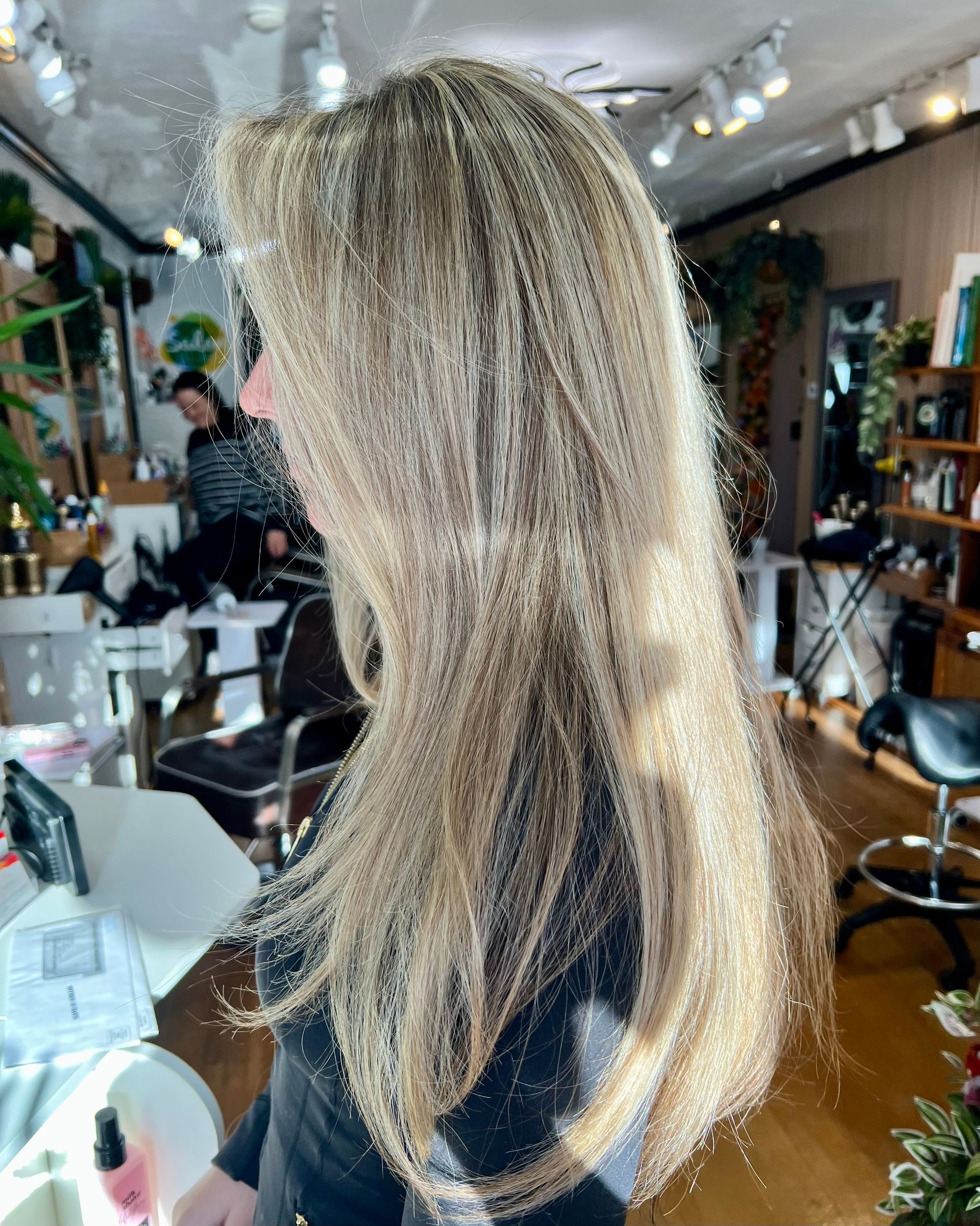 A woman with long blonde hair is standing in a salon.