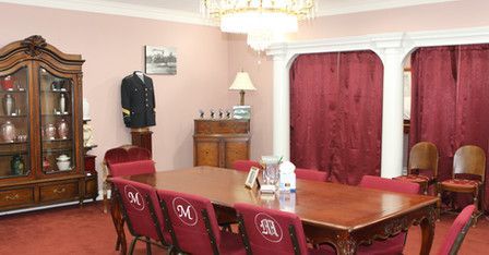 A dining room with a long wooden table and red chairs.