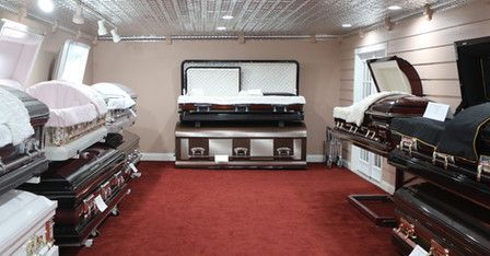 A room filled with lots of coffins and a red carpet.