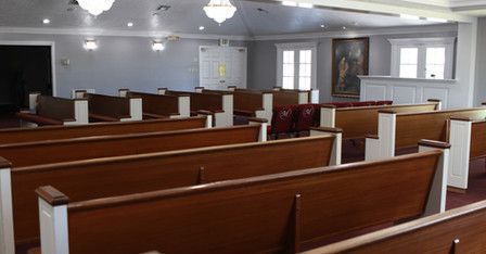 There are rows of wooden benches in a church.