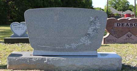 A gravestone with flowers on it is in a cemetery.