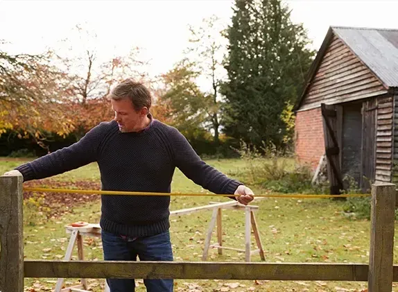 A man is installing a wooden deck with a drill.