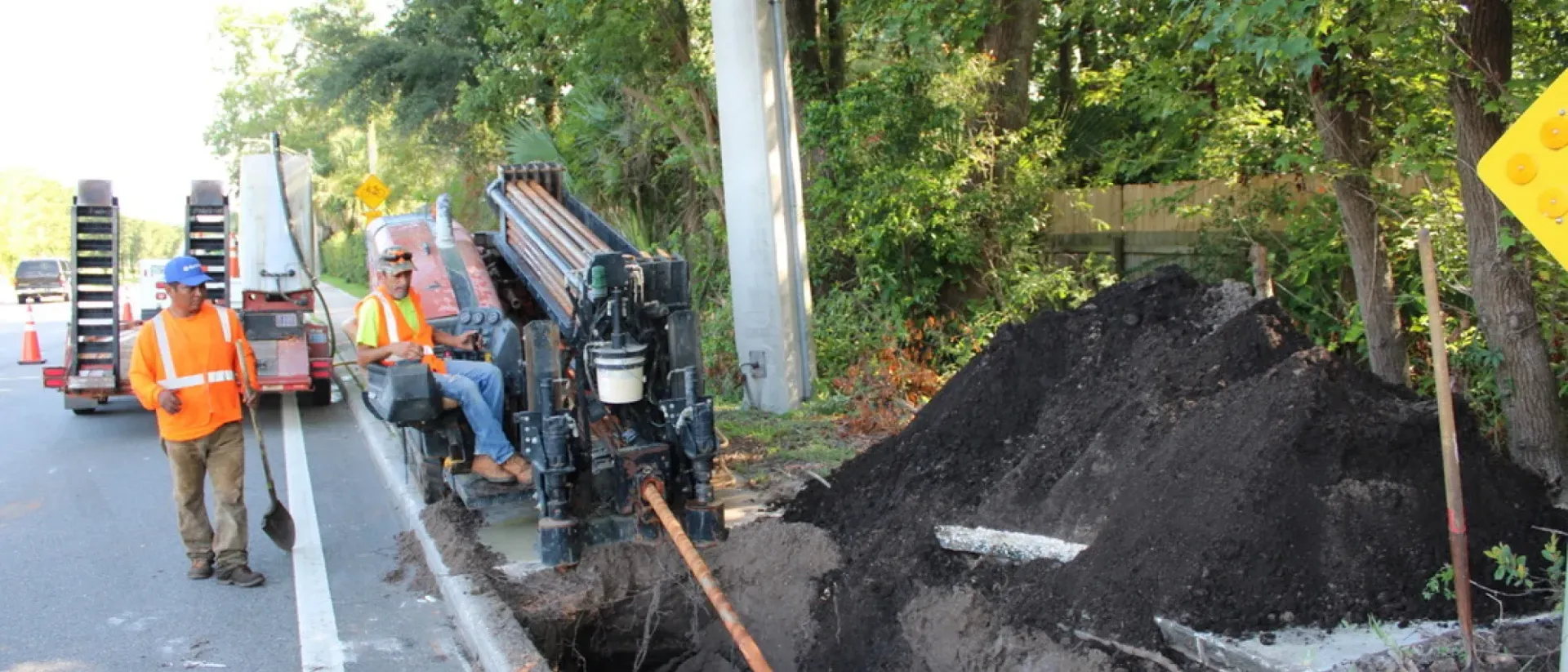 A man is walking down a street next to a pile of dirt.