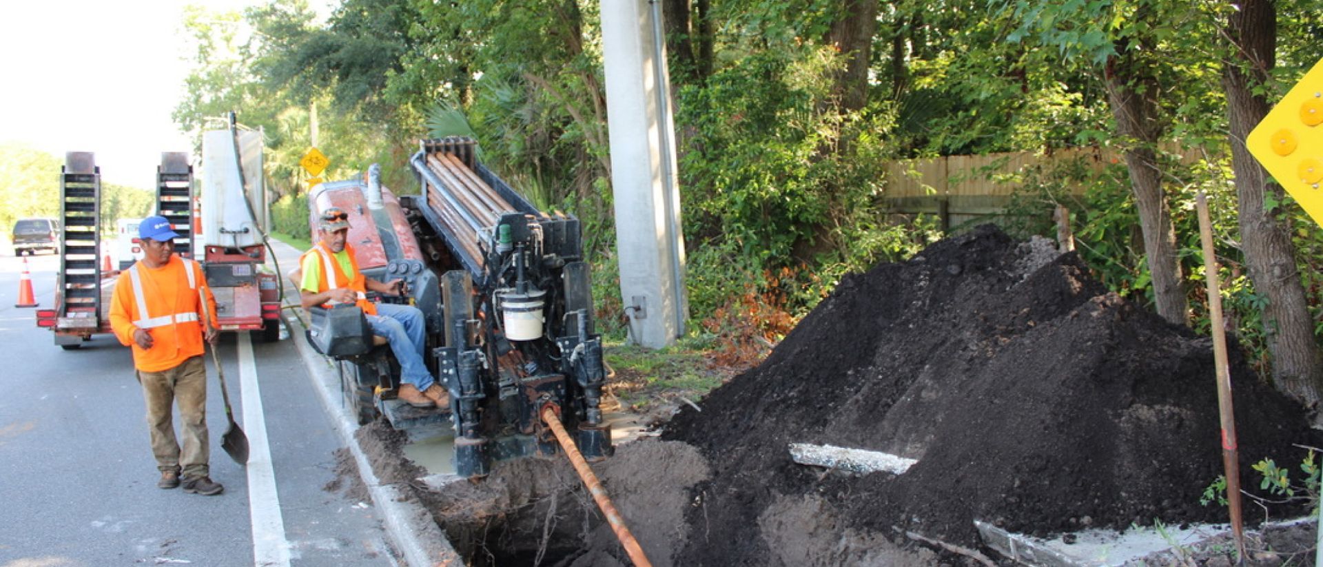 A group of construction workers are working on the side of a road.