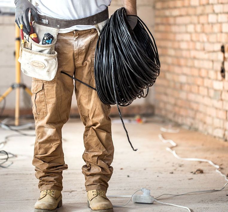 A man is standing in a room holding a roll of wires.
