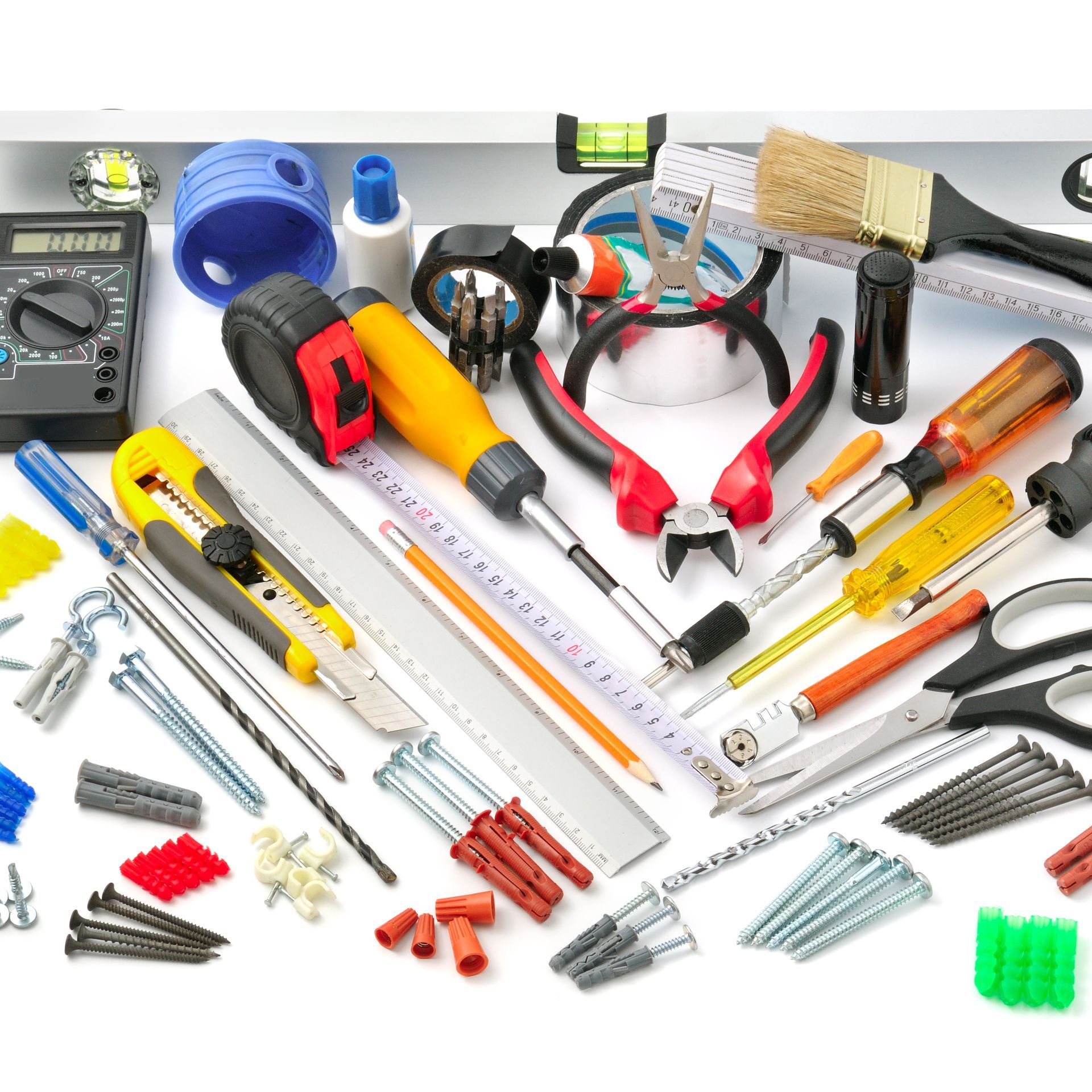 Vari utensili, tra cui cacciaviti, pinze, livella, metro a nastro e viti, disposti su una superficie bianca.