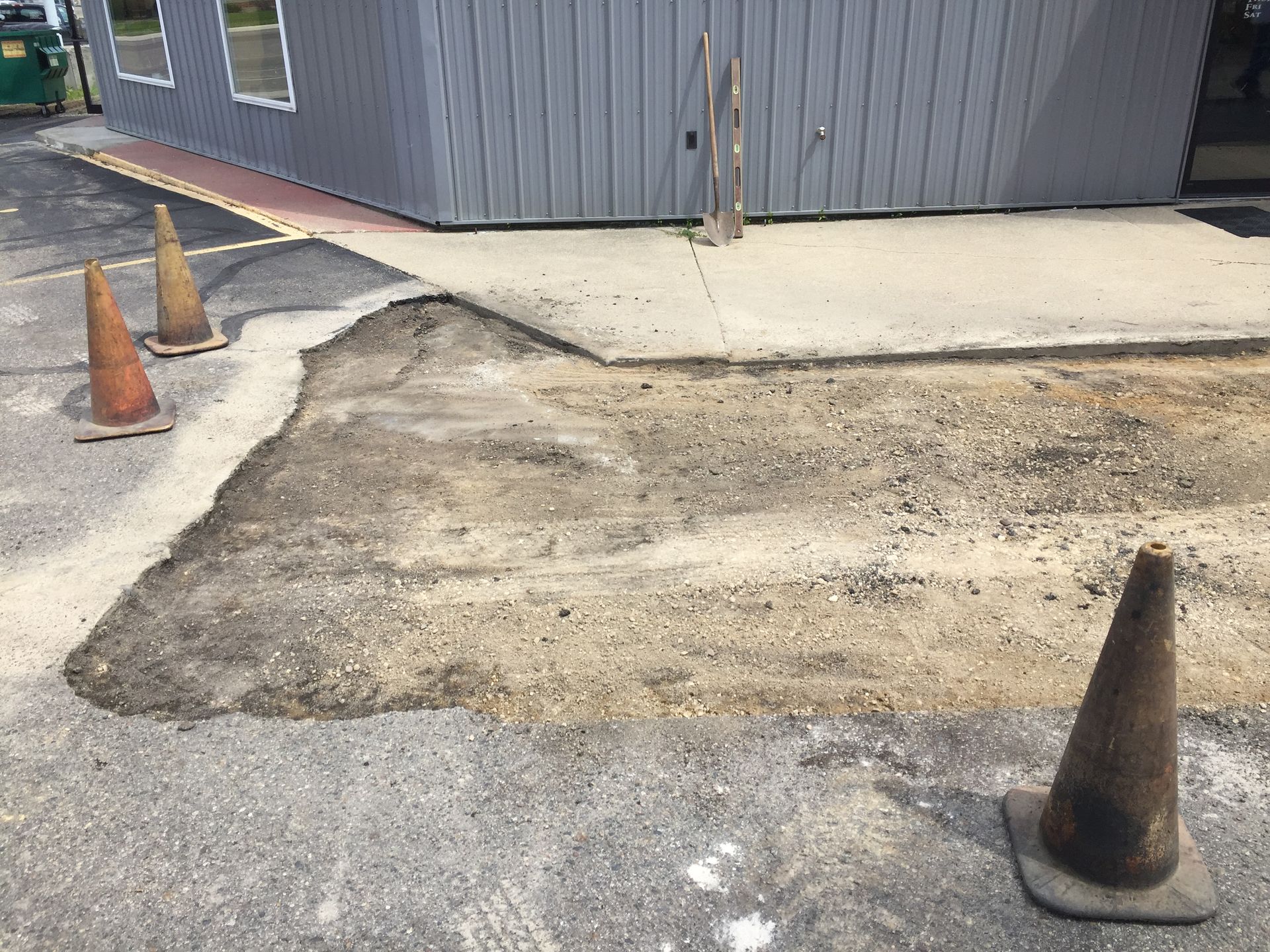 Three traffic cones are sitting on the ground in front of a building.