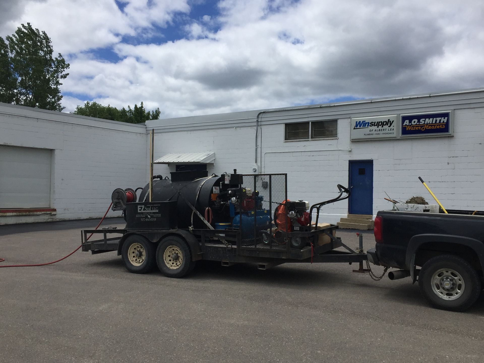 A truck with a trailer attached to it is parked in front of a building