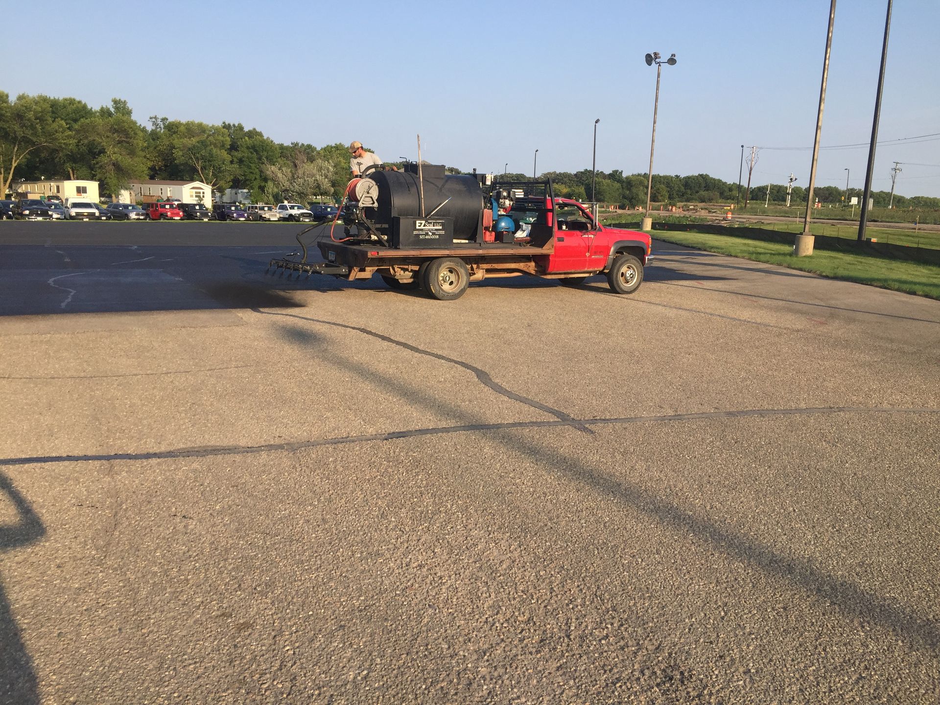 A red truck is driving down a road with a trailer attached to it.