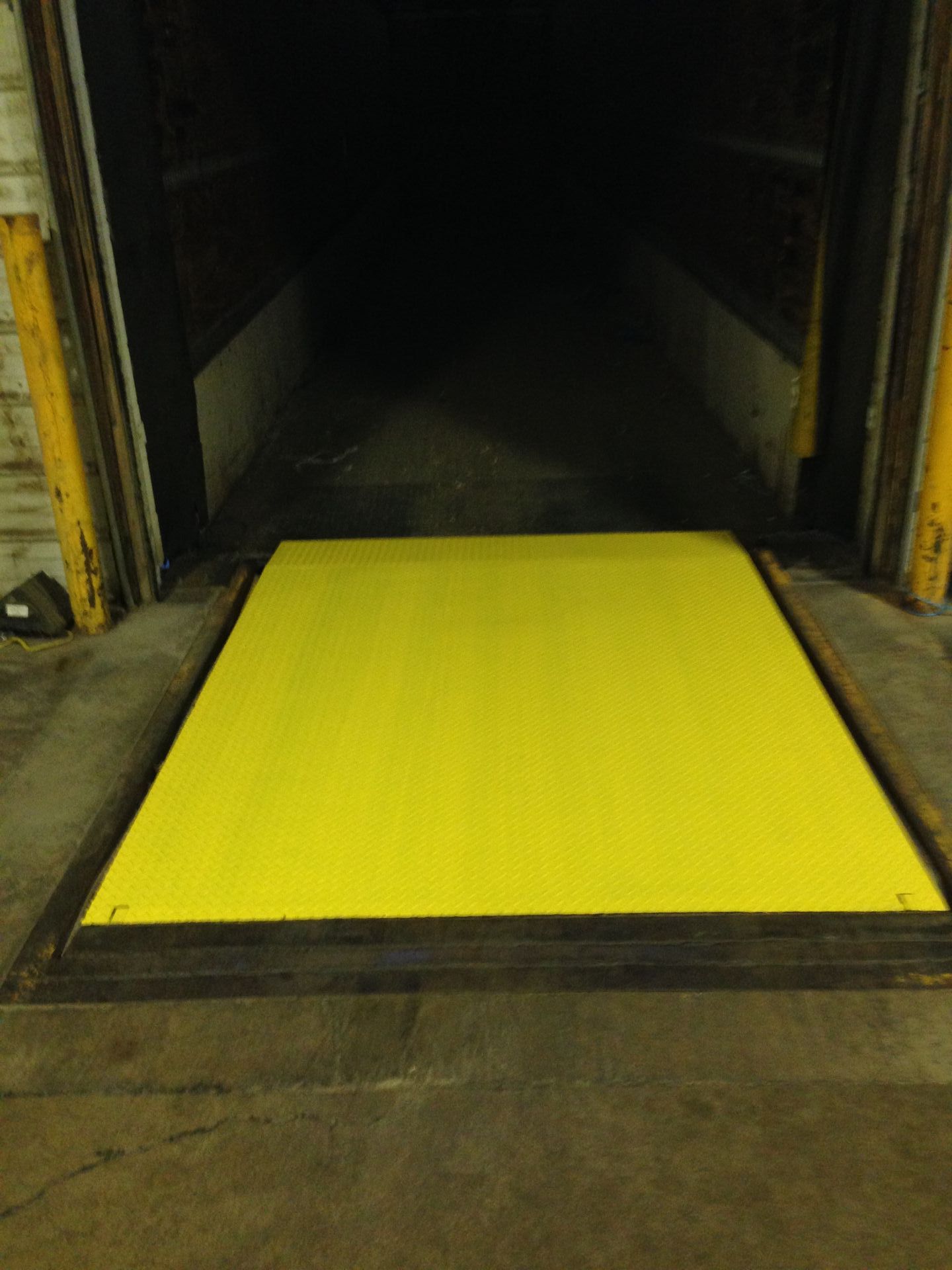 A yellow door with a black frame is open to a dark room