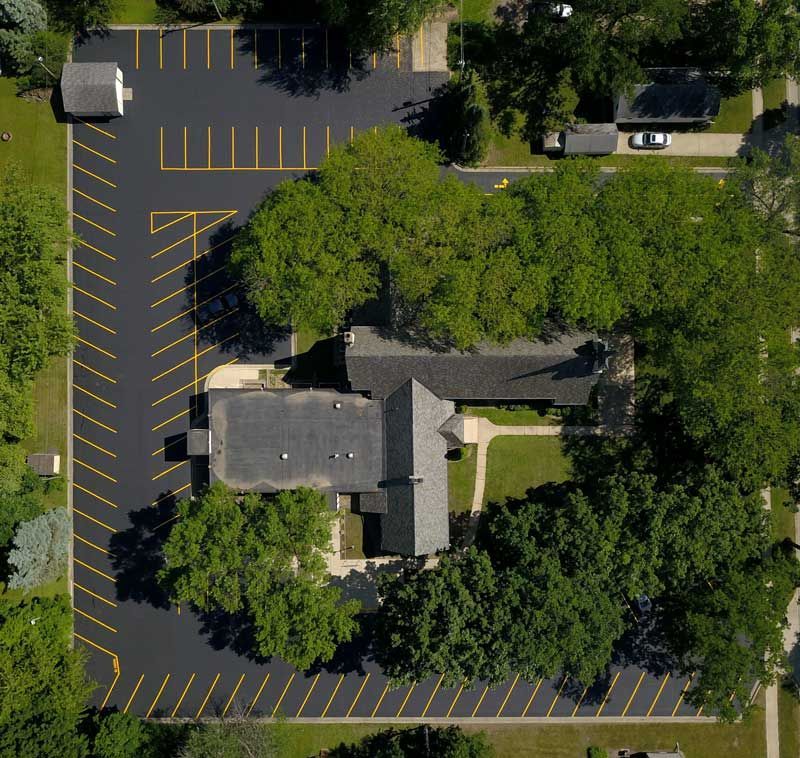 An aerial view of a parking lot with a house in the background