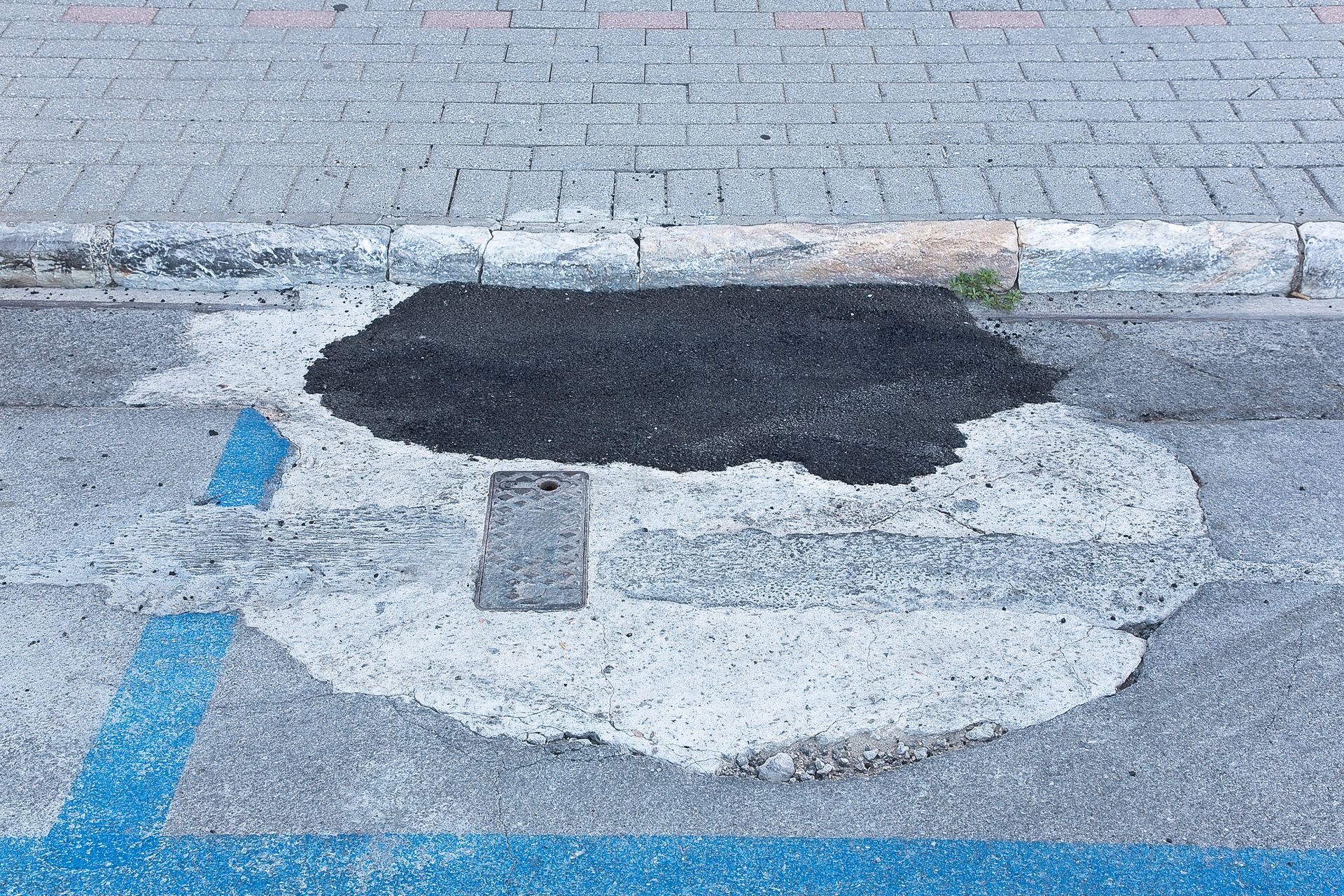 A man is applying asphalt to a curb with a roller