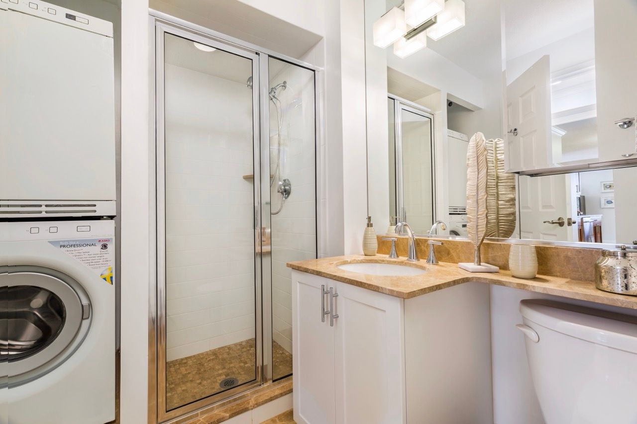 Bathroom featuring a glass shower enclosure, stacked washer/dryer, and a vanity with sink.