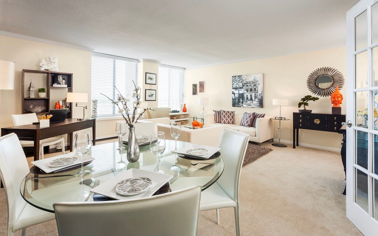 Open-plan living area with glass dining table, white chairs, and cream furnishings.