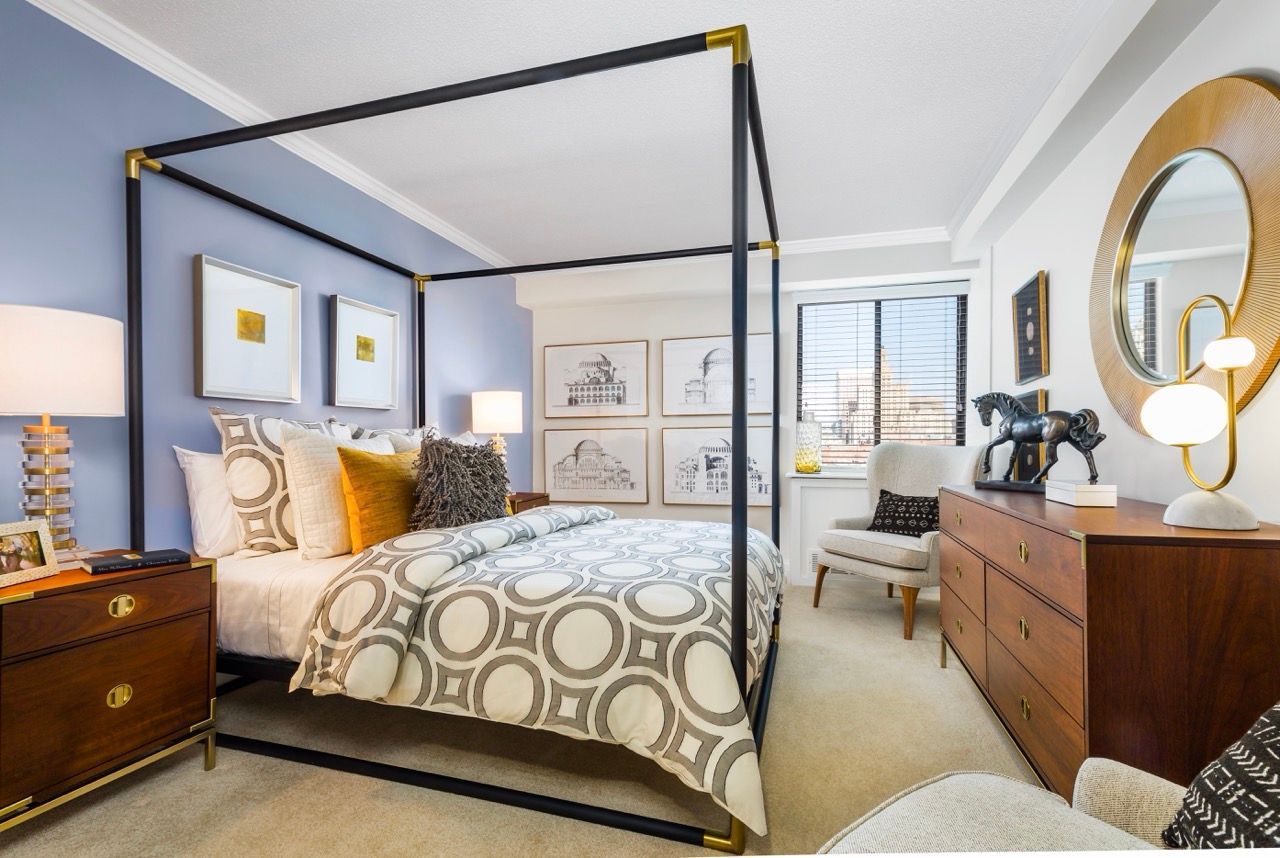 Bedroom with a dark metal four-poster bed, blue accent wall, nightstands, dresser, and window.